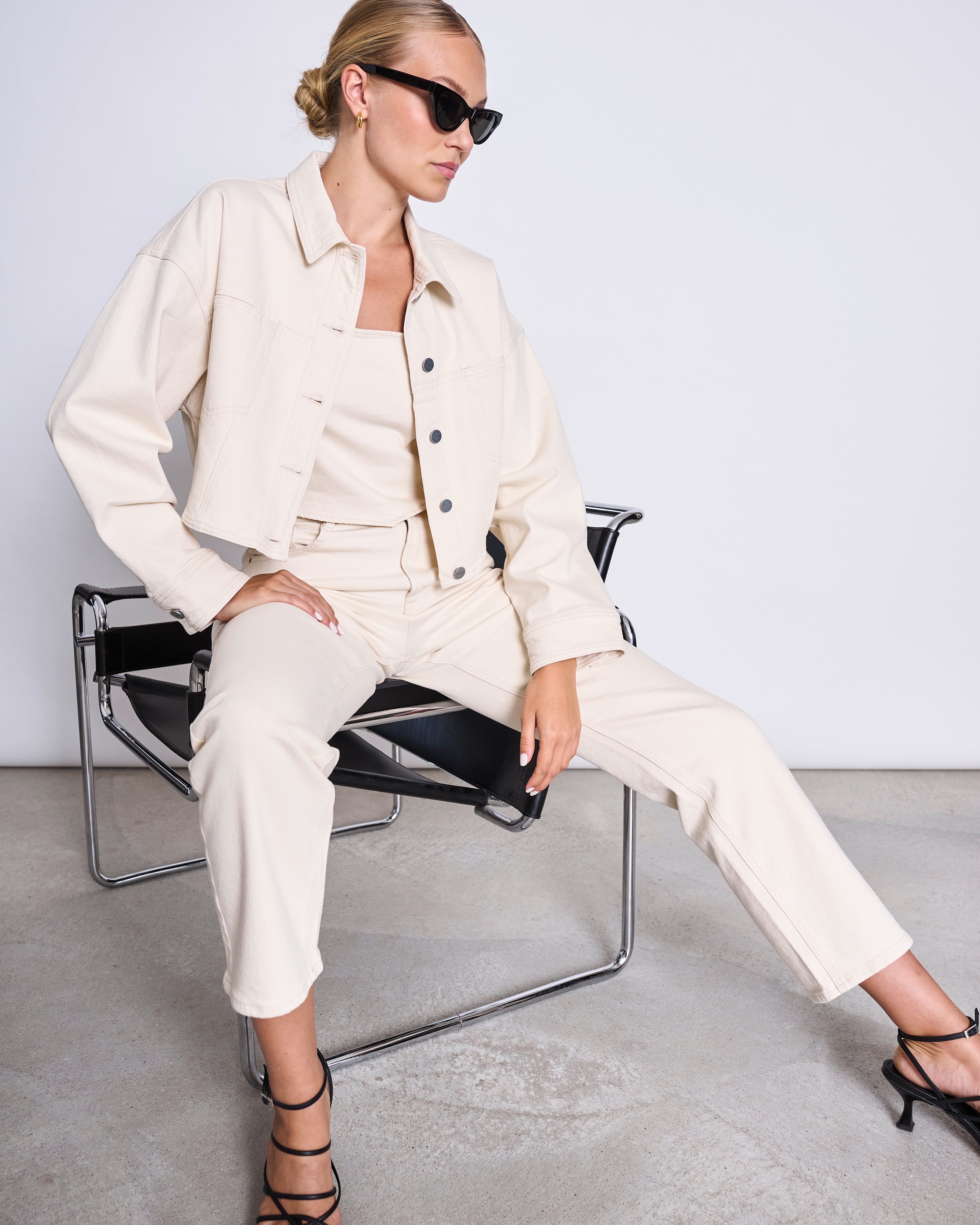 ARIA Boxy Cropped Jeansjacke in Ecru mit Knopfleiste, klassischem Kragen und zwei Brusttaschen; Model im hellen Co-ord-Look.