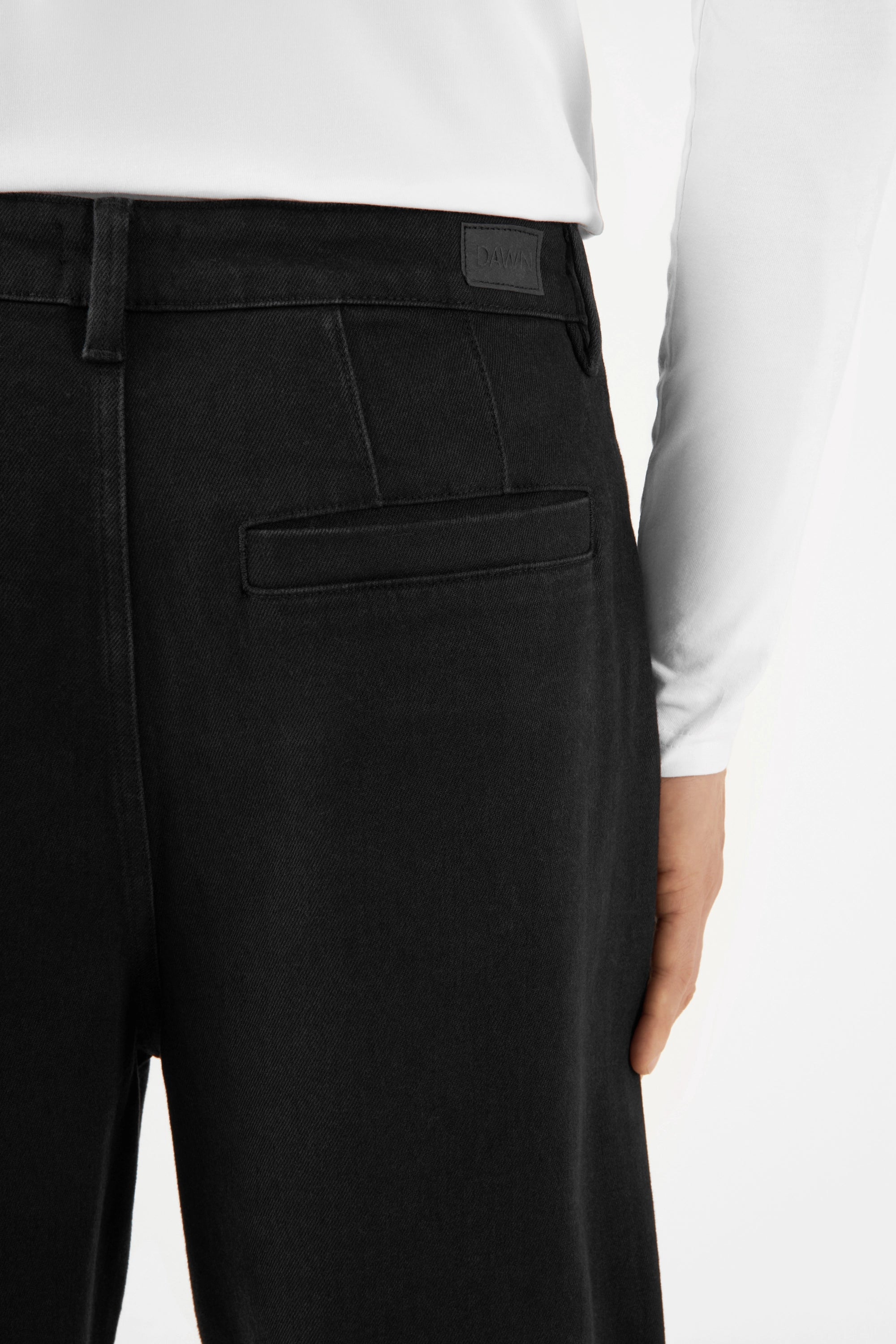 Schwarze ASTER Balloon-Fit Hose aus TENCEL, mittelhoher Bund, weite Hüften/Oberschenkel, zum Saum hin schmal; Rückentasche und Bund-Label sichtbar.