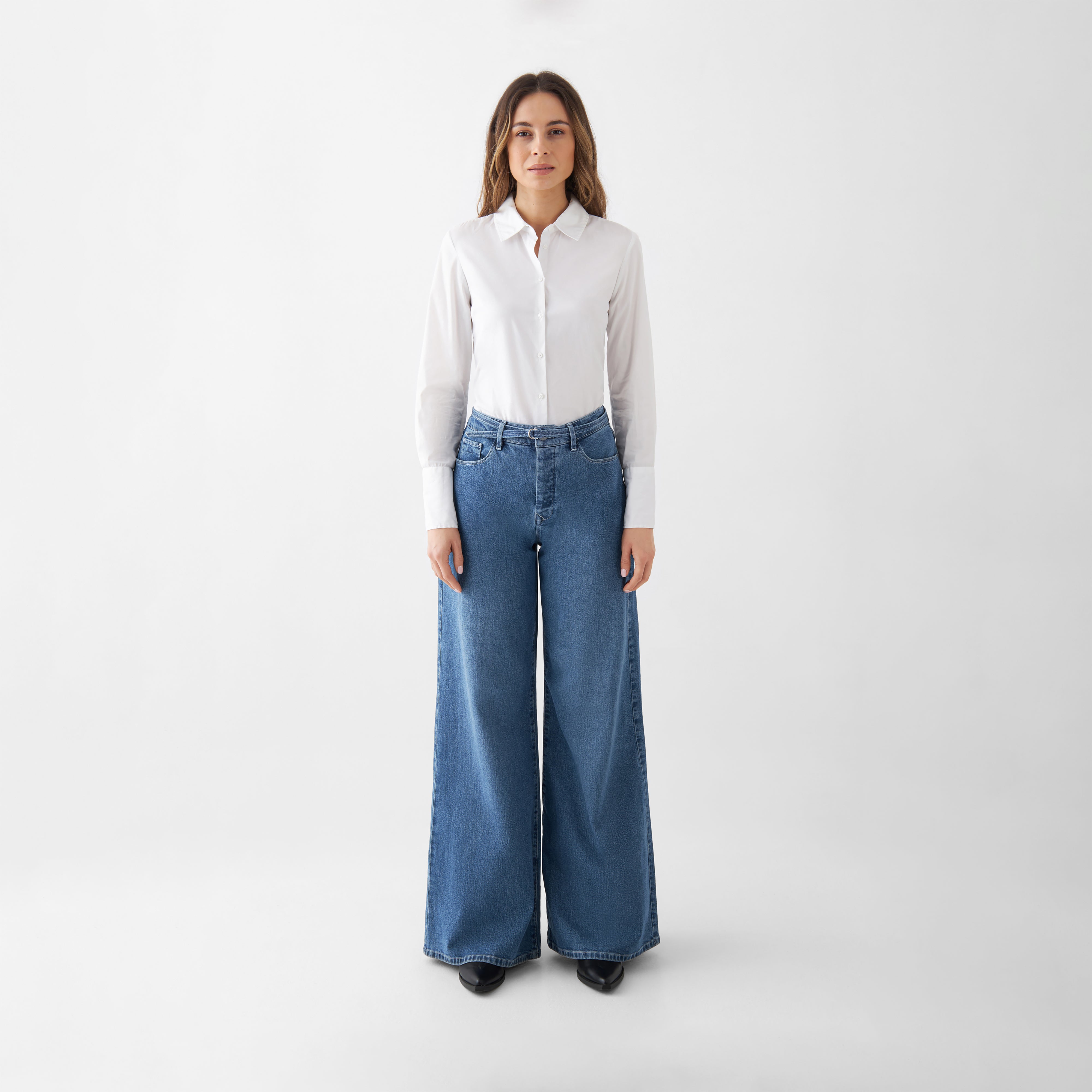 Frontansicht einer Frau in BLAZE High-Waist 5-Pocket-Jeans in Medium Blue mit weitem Bein und weißem Hemd.
