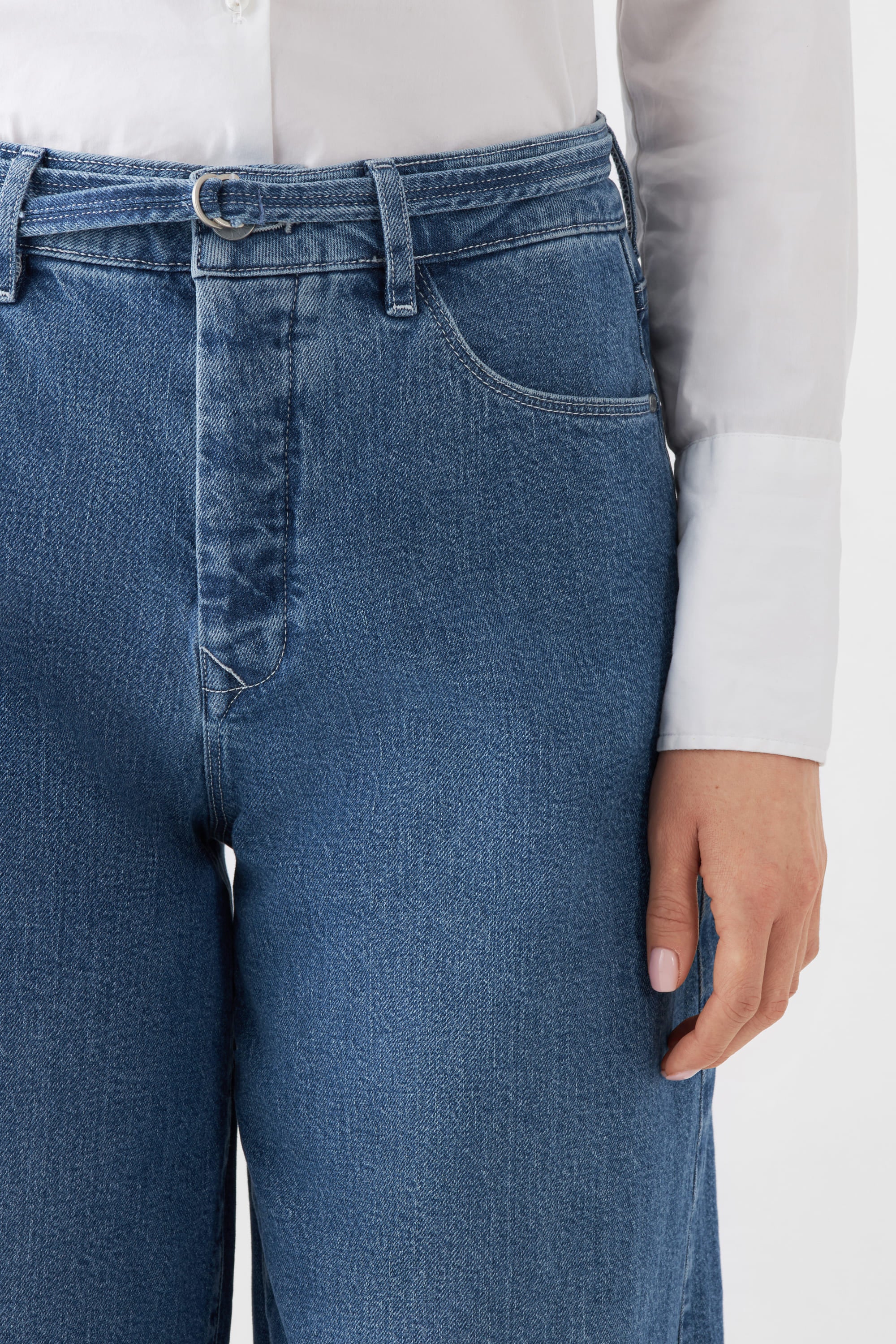 Frontansicht der BLAZE High-Waist Jeans in Medium Blue mit weitem Bein, Gürtelschlaufen und Metallring-Detail; Bio-Baumwolle.