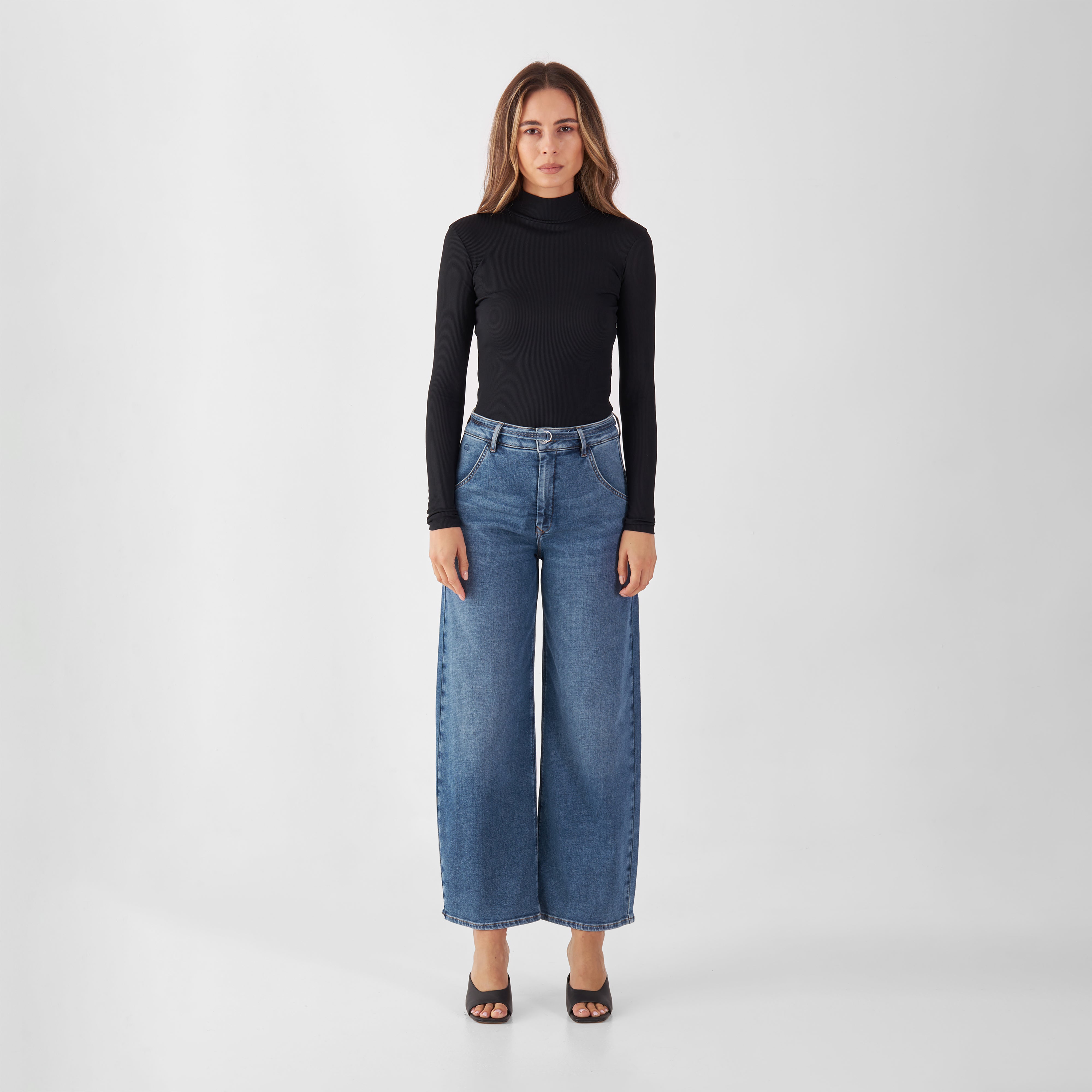 Modell trägt Vintage Blue BLINK High-Waist Culotte-Jeans mit hohem Bund und weitem, gekürztem Bein aus Denim.