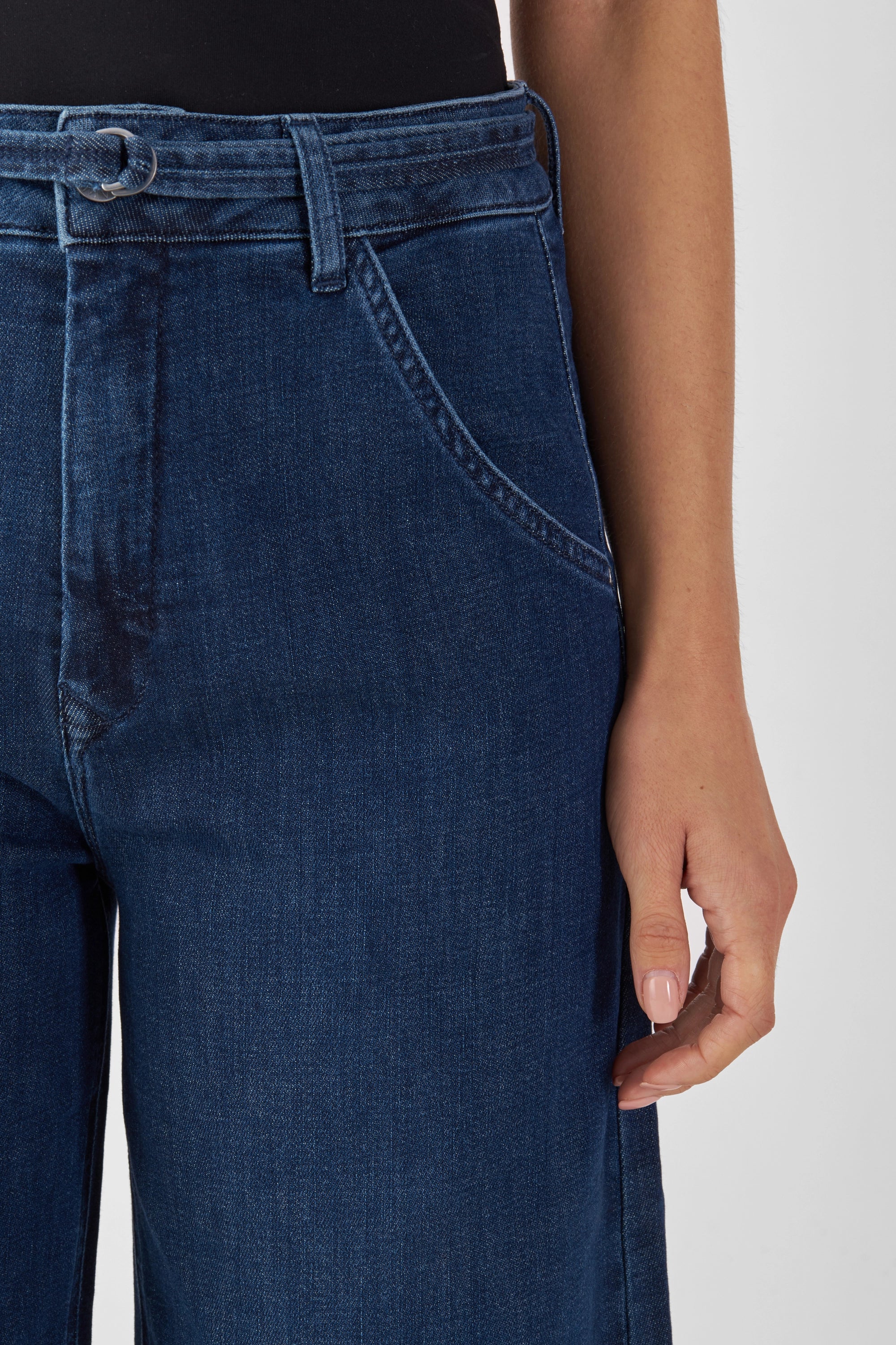Dunkelblaue BLINK High-Waist-Jeans: weites, gerades Bein, hohe Taille, Gürtelring-Detail und vordere Tasche – Nahaufnahme am Körper.