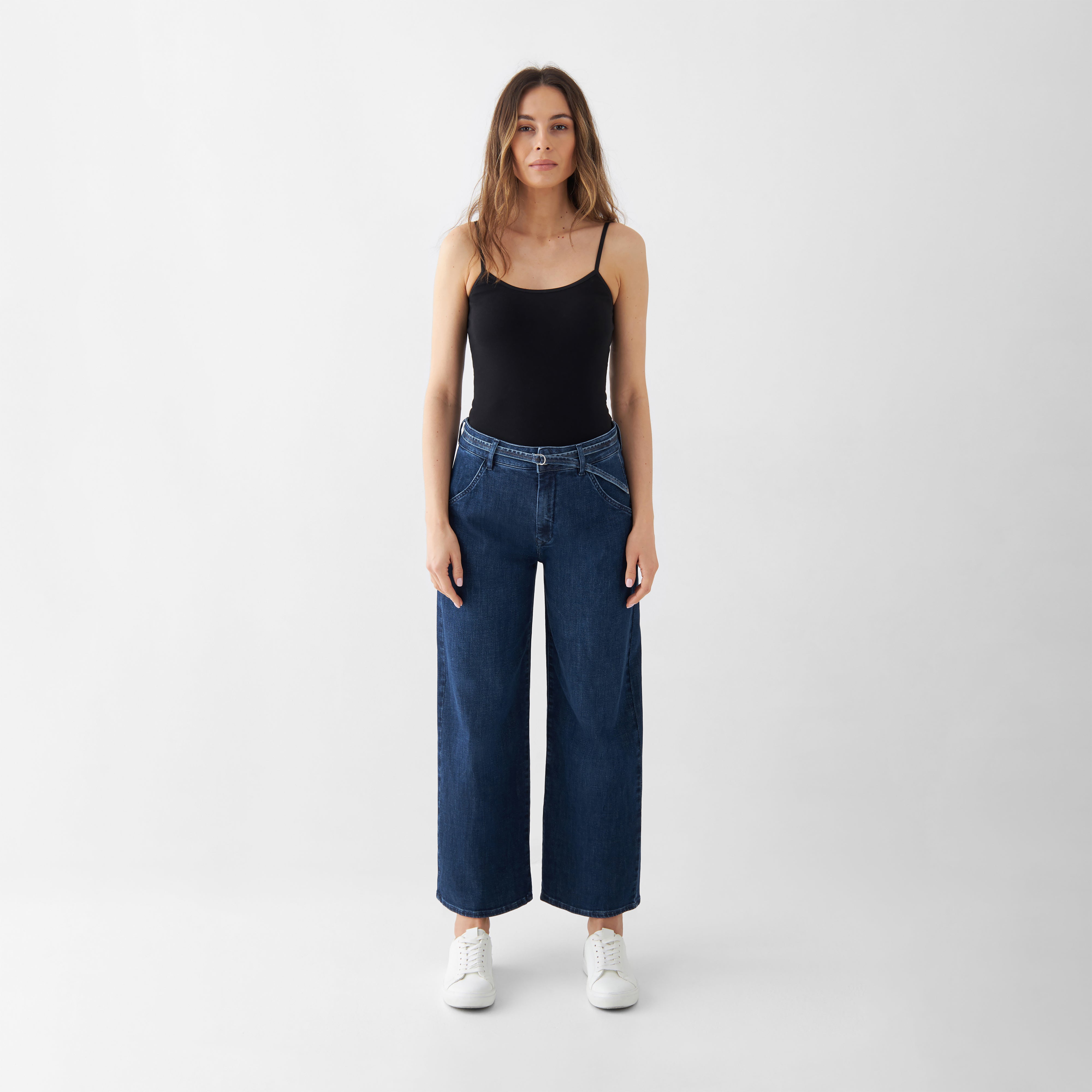 Dunkelblaue High-Waist-Culotte-Jeans mit weitem Bein; abnehmbarer Gürtel, getragen von einer Frau in schwarzem Top.