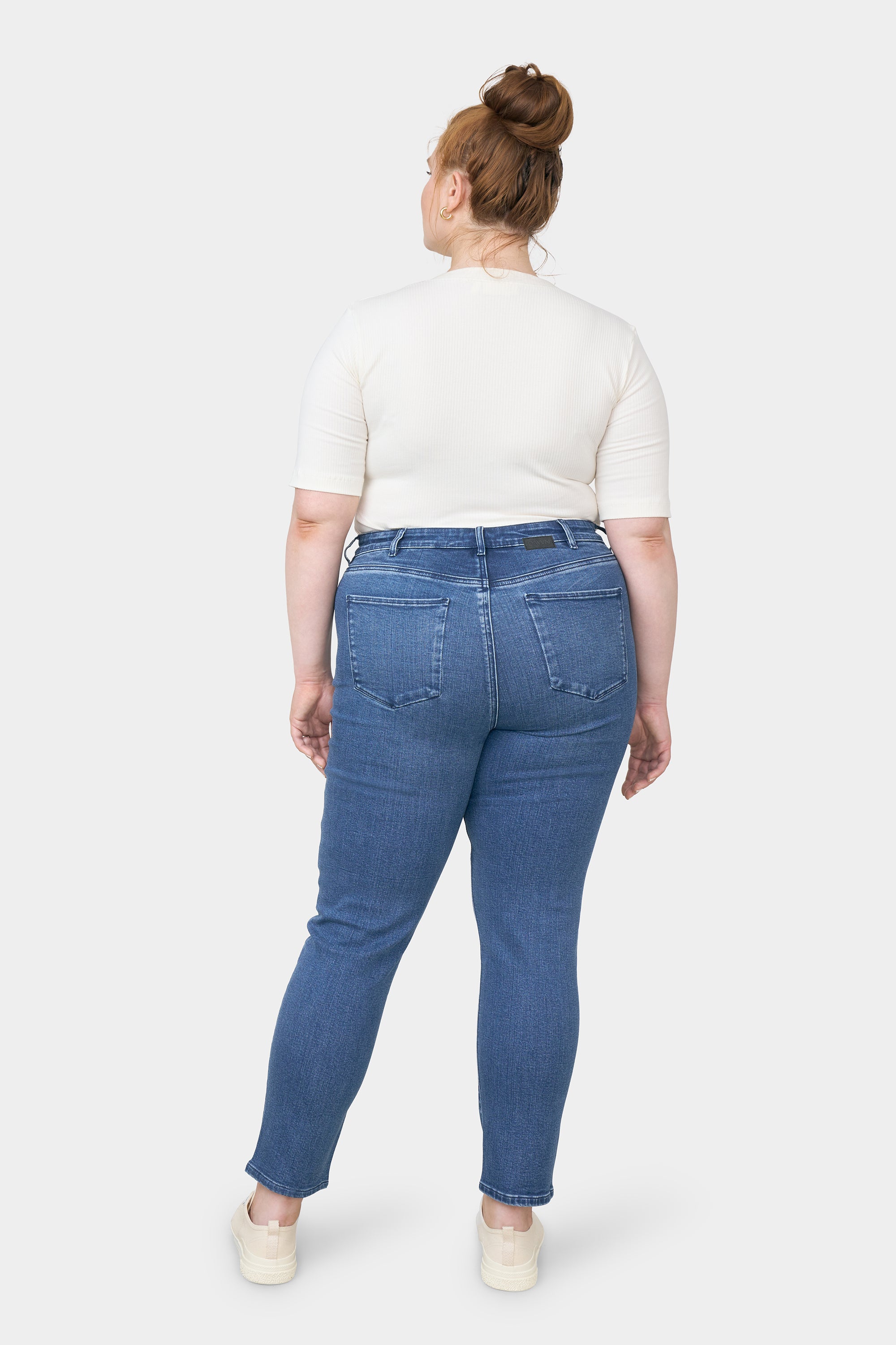 Rückenansicht einer Frau in dunkelblauer SUN UP Skinny-Jeans mit mittlerer Taille und zwei Gesäßtaschen.