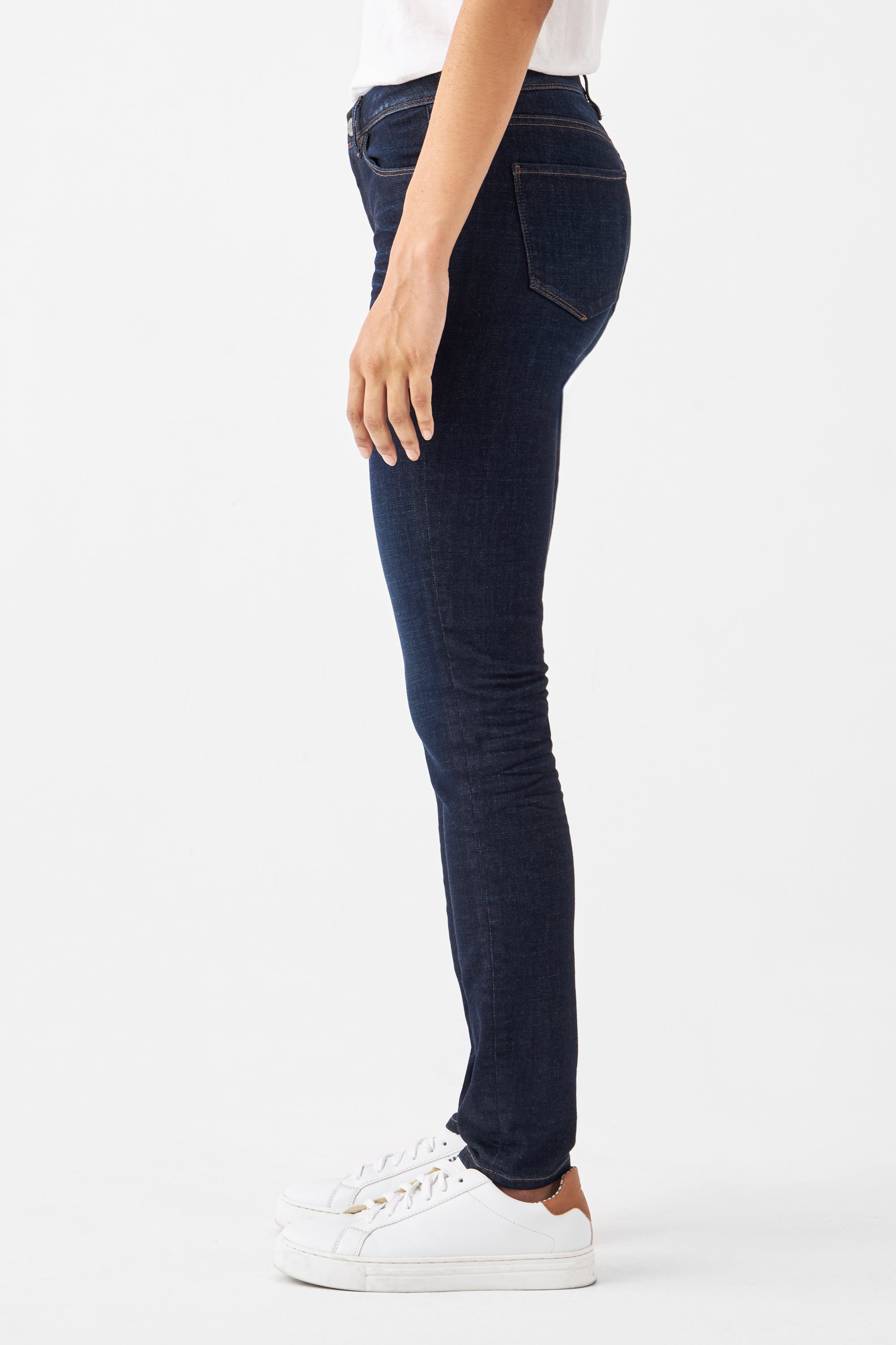 Dunkelblaue Slim-Fit Jeans aus Organic Comfortstretch – Low-Waist, 5-Pocket-Design; Seitenansicht eines Models in weißen Sneakern.