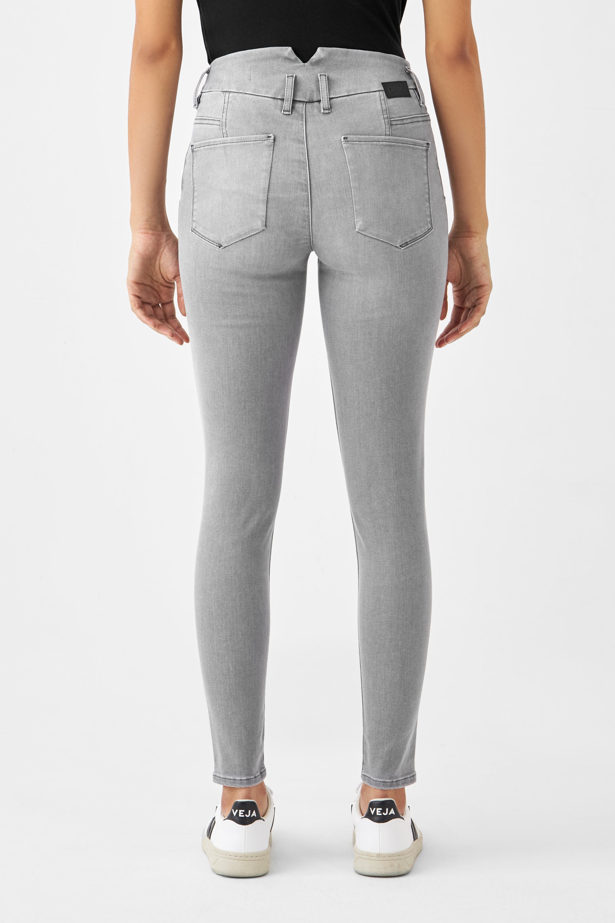 Rückansicht einer silbergrauen SUN UP Skinny Jeans in Powerstretch, mit zwei Gesäßtaschen und Gürtelschlaufen, getragen zu weißen Sneakers.