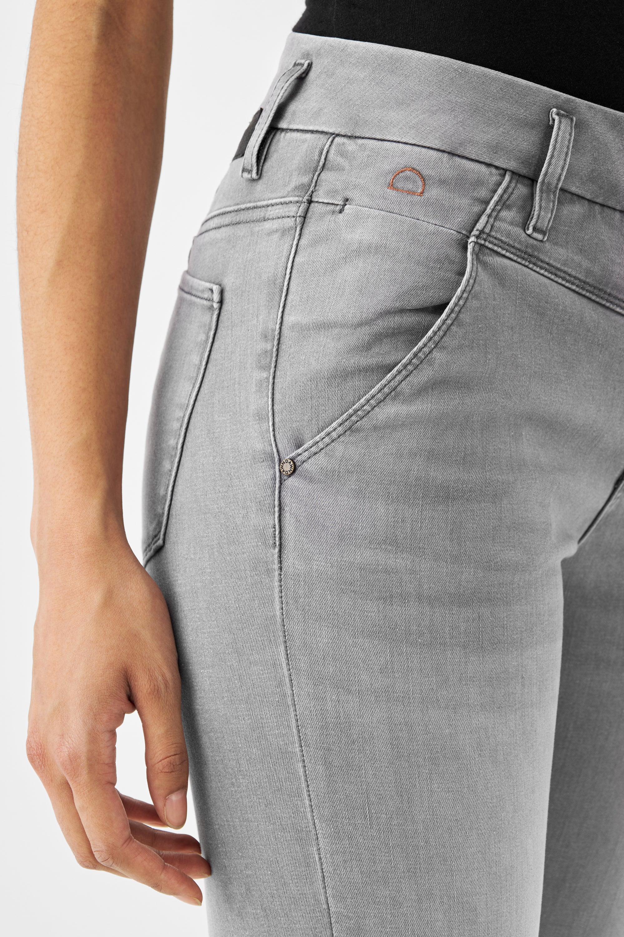 Hellgraue SUN UP Skinny Jeans von DAWN (Silver Denim) mit Gürtelschlaufen, schräge Außennaht und kleinem orangenem Halbmond-Logo am Bund.