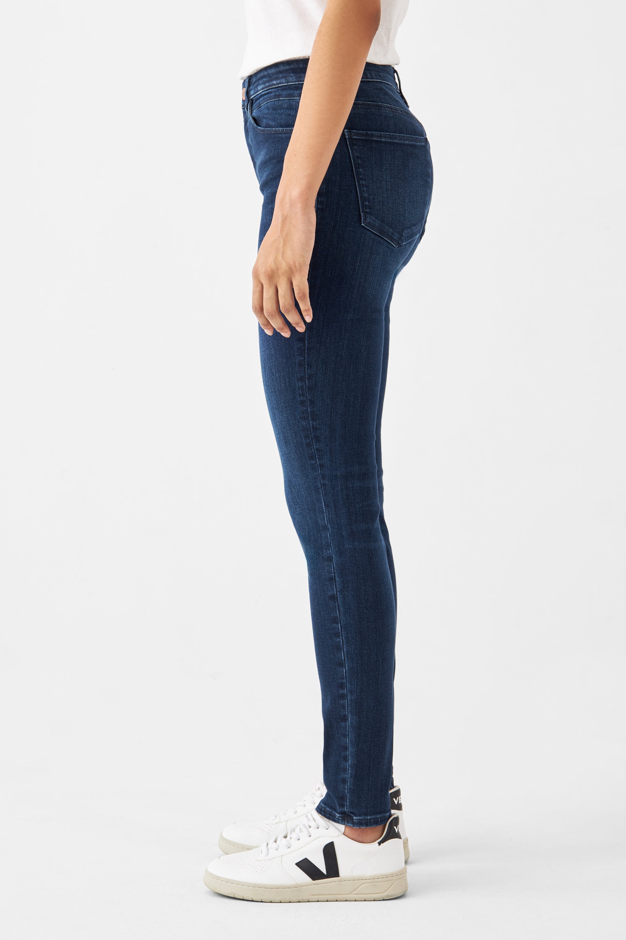 Seitenansicht einer dunkelblauen SUN UP Skinny Jeans Basic aus Powerstretch, mittig sitzend, figurschmeichelnd, mit weißen Sneakern.