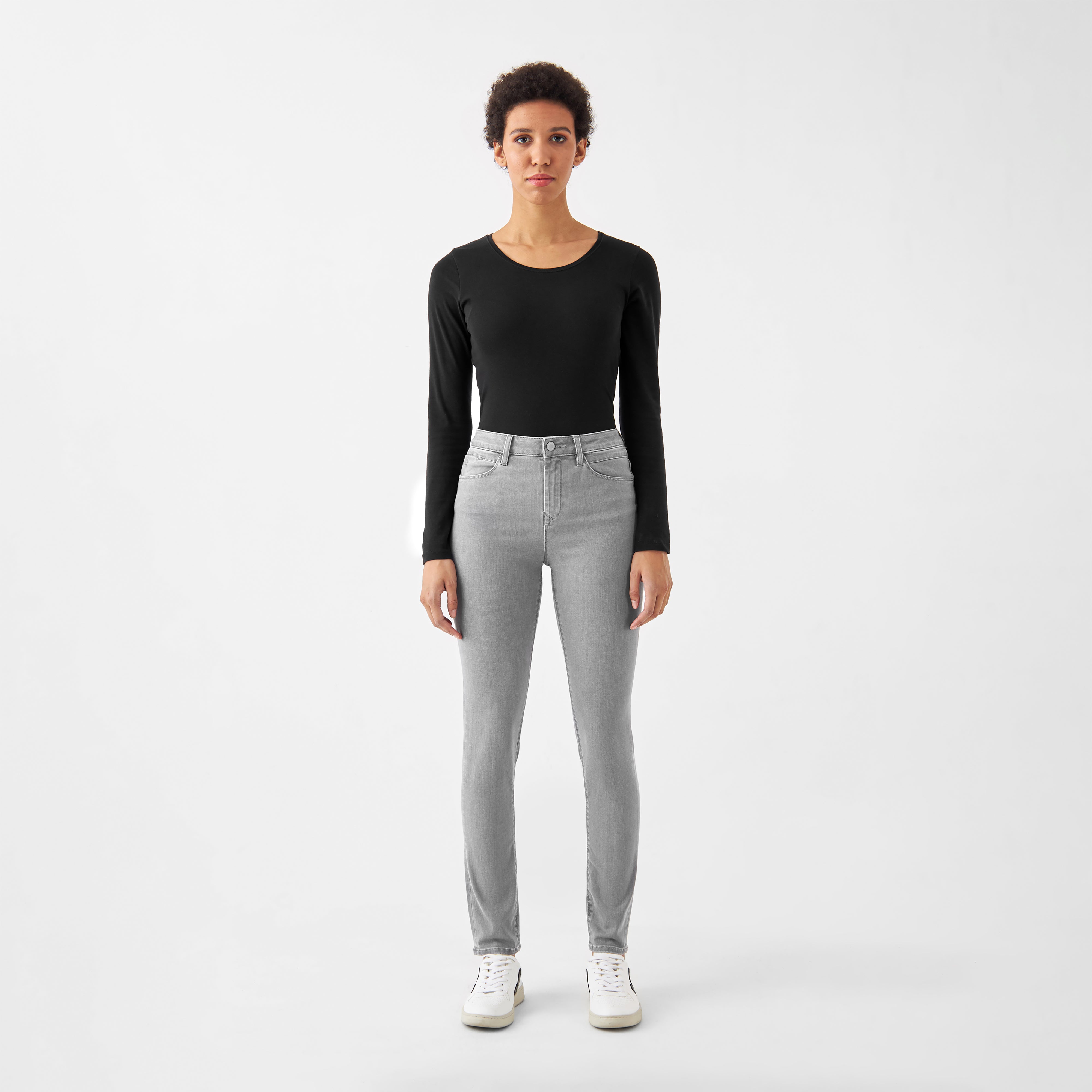 Modelbild: hellgraue SUN UP Skinny Powerstretch Jeans (Silver Denim) – Mid-Rise, minimalist Fronttaschen; schwarzes Langarm-Top, weiße Sneaker.