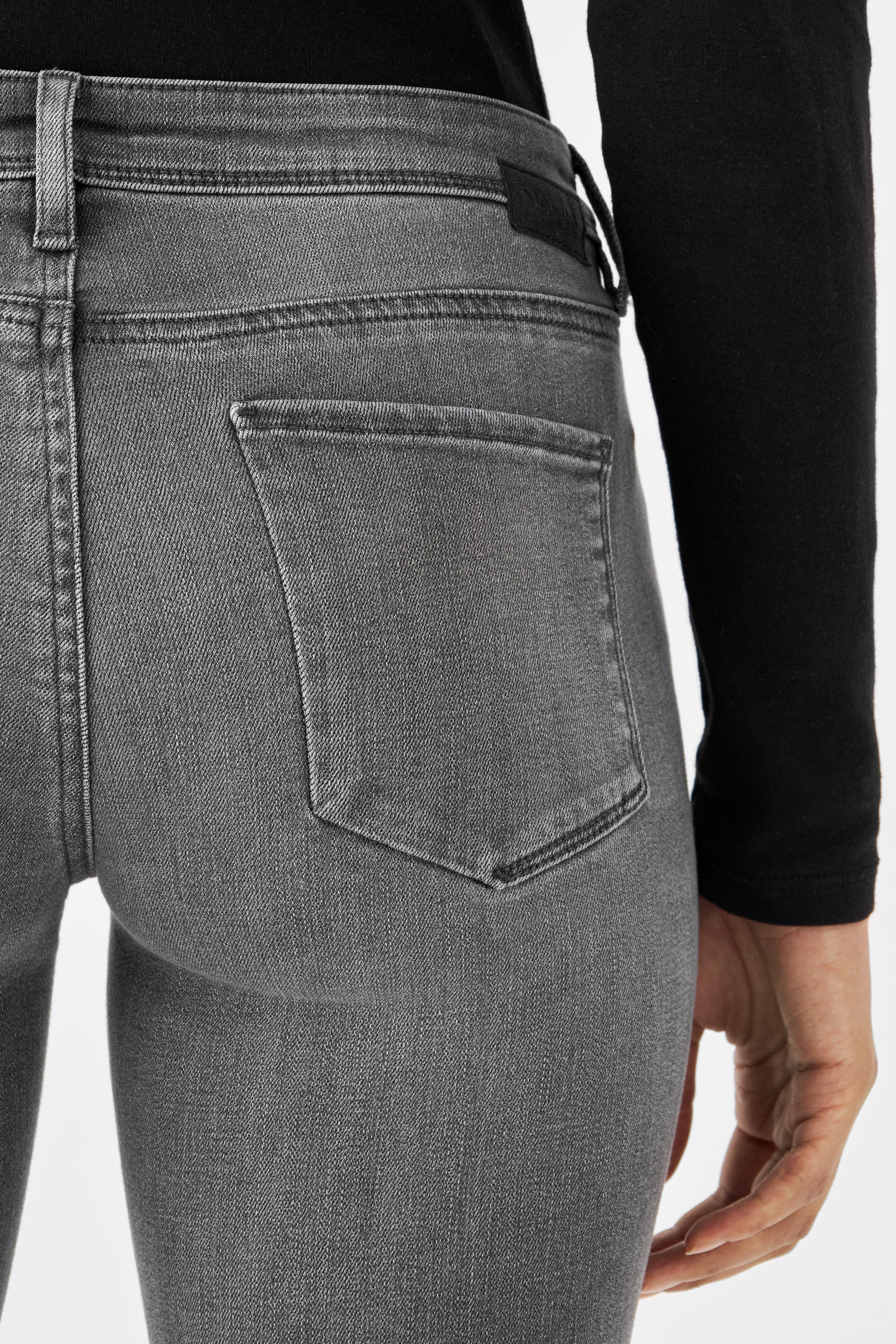Graue MID SUN Slim Comfortstretch Jeans von DAWN Denim, Rückseite mit sichtbarer Hintertasche, Bundnähten; schwarzes Oberteil.