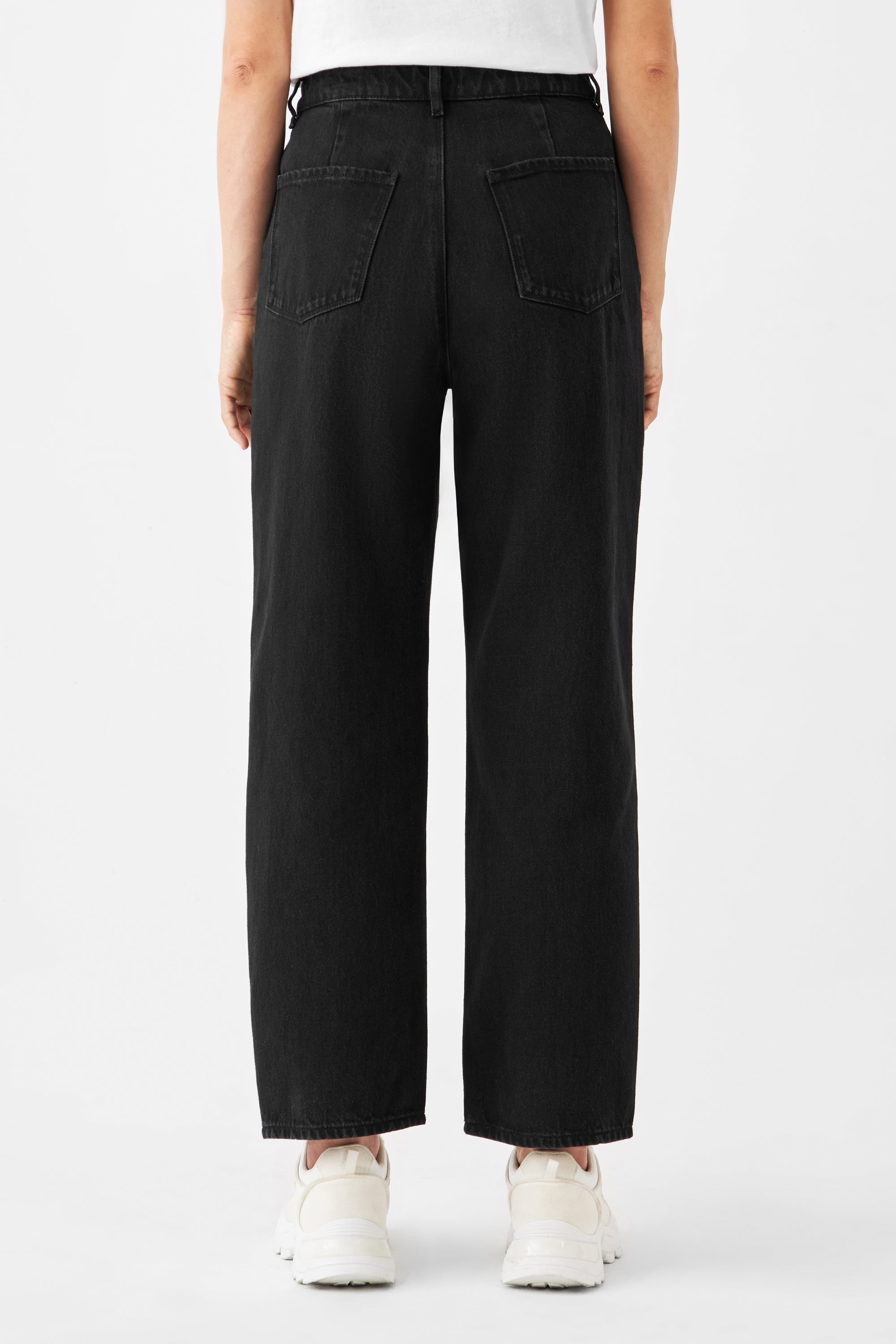 Rückansicht der schwarzen DAWN Denim-Jeans aus Bio-Baumwolle, High-Waist, weiter gerader Beinverlauf, zwei Gesäßtaschen – minimalistisch und ohne Stretch, mit weißen Sneakern getragen.