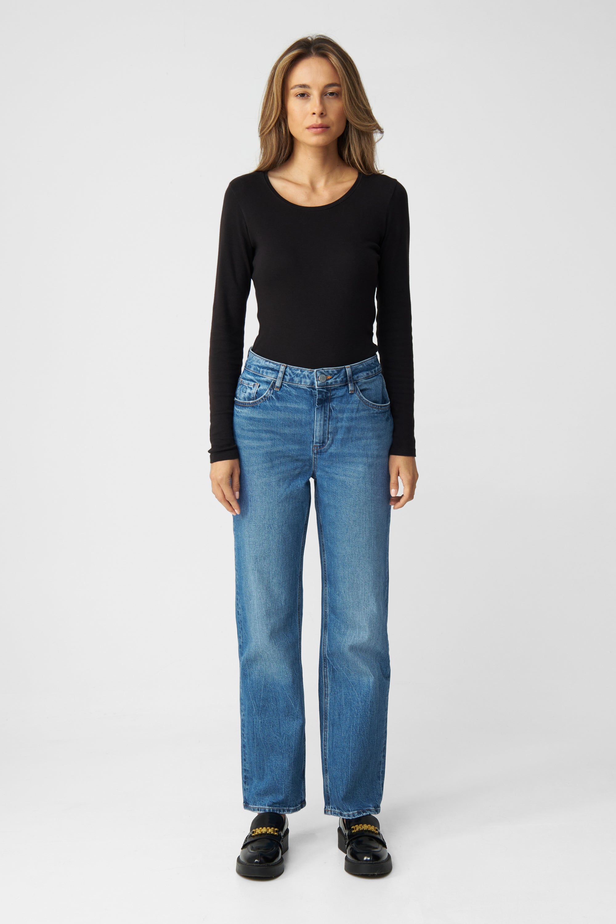 Frontansicht einer Frau in schwarzem Oberteil, trägt MORNING Jeans in Medium Blue – Regular Straight, 5-Pocket-Design, mit leichtem Stretch.