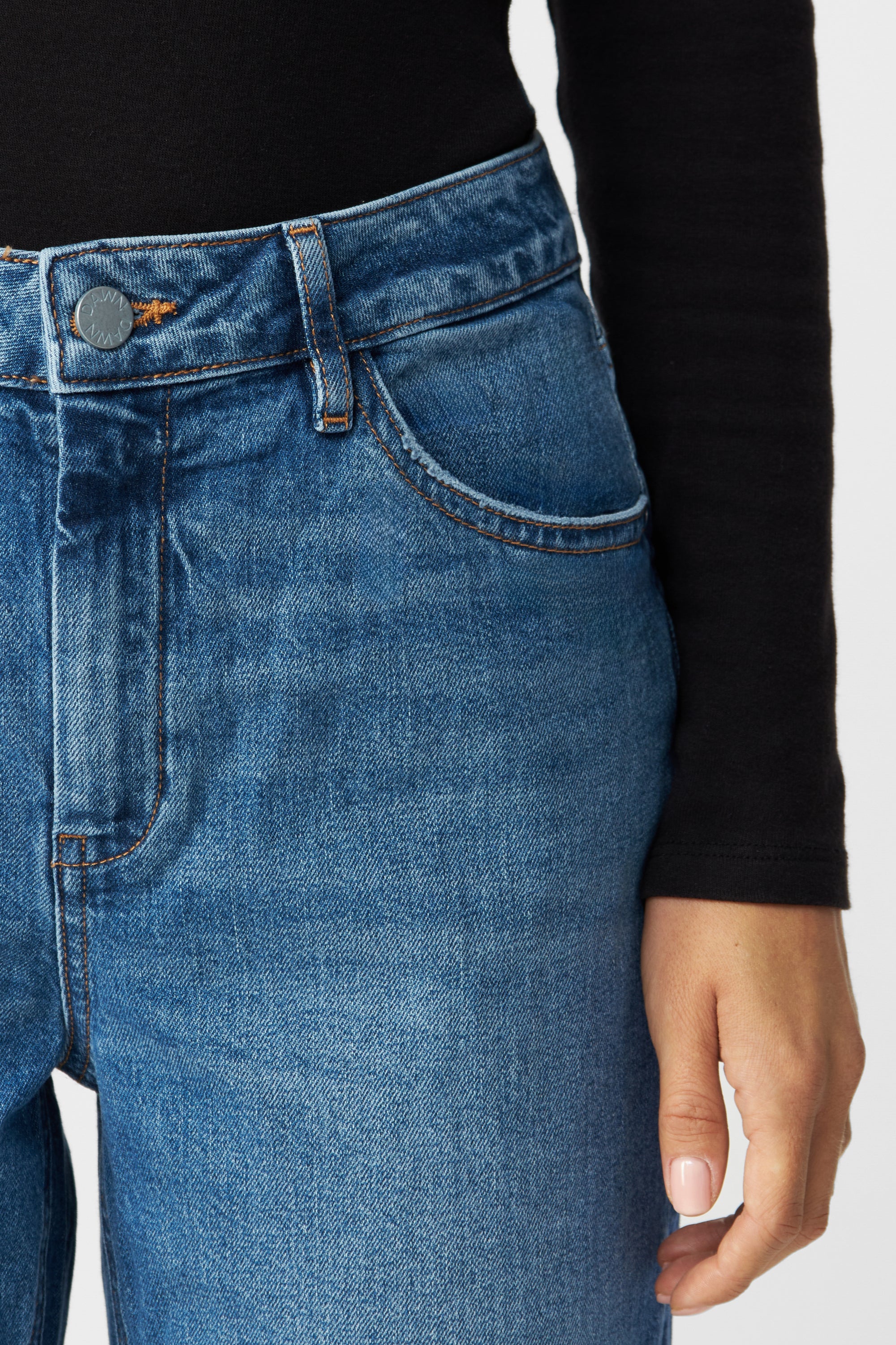 DAWN MORNING Jeans in Medium Blue, Regular Straight mit Minimal Stretch; 5-Pocket-Design, mittige Taille, Knopf mit DAWN-Logo und kontrastfarbene Nähte (Nahaufnahme Taillenbereich).