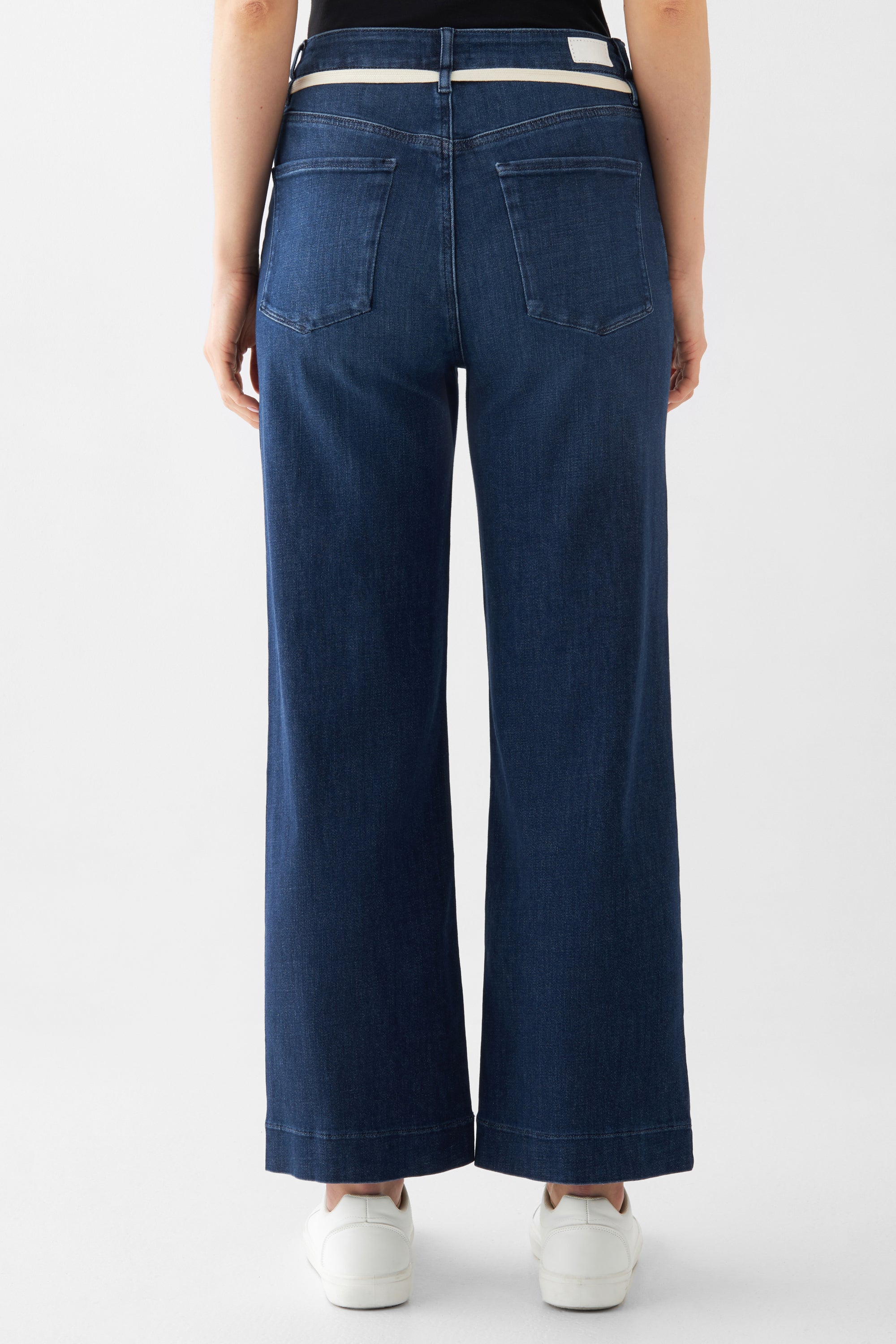 Dunkelblaue DEW Cropped French Pocket Jeans, hohe Taille, ausgestelltes Bein, Rückansicht mit zwei Gesäßtaschen, beiger Gürtel.