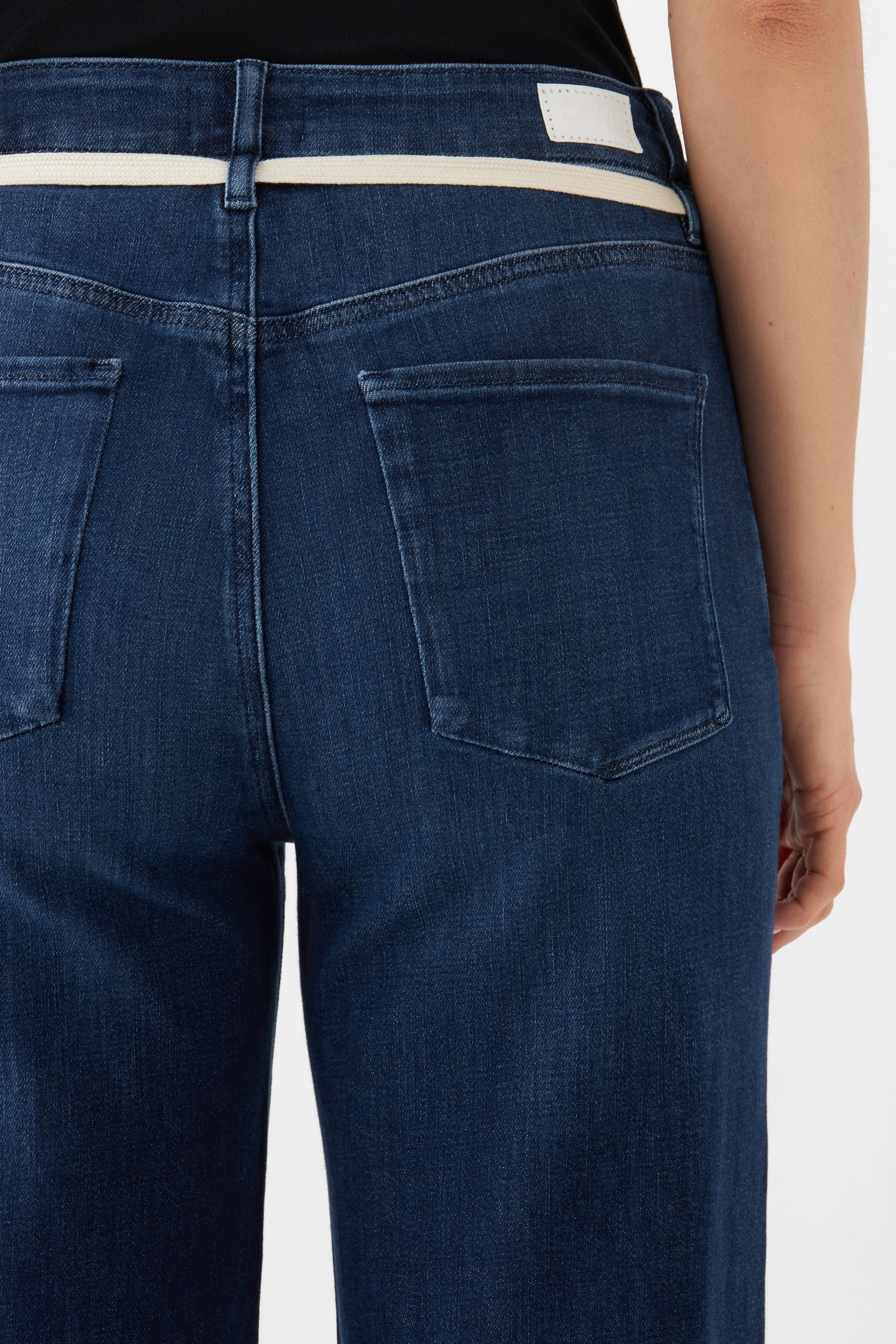 Dunkelblaue DEW Cropped Flared Jeans mit hohem Bund und ausgestelltem Bein; Rückenansicht mit zwei Gesäßtaschen und weißem Patch am Bund.