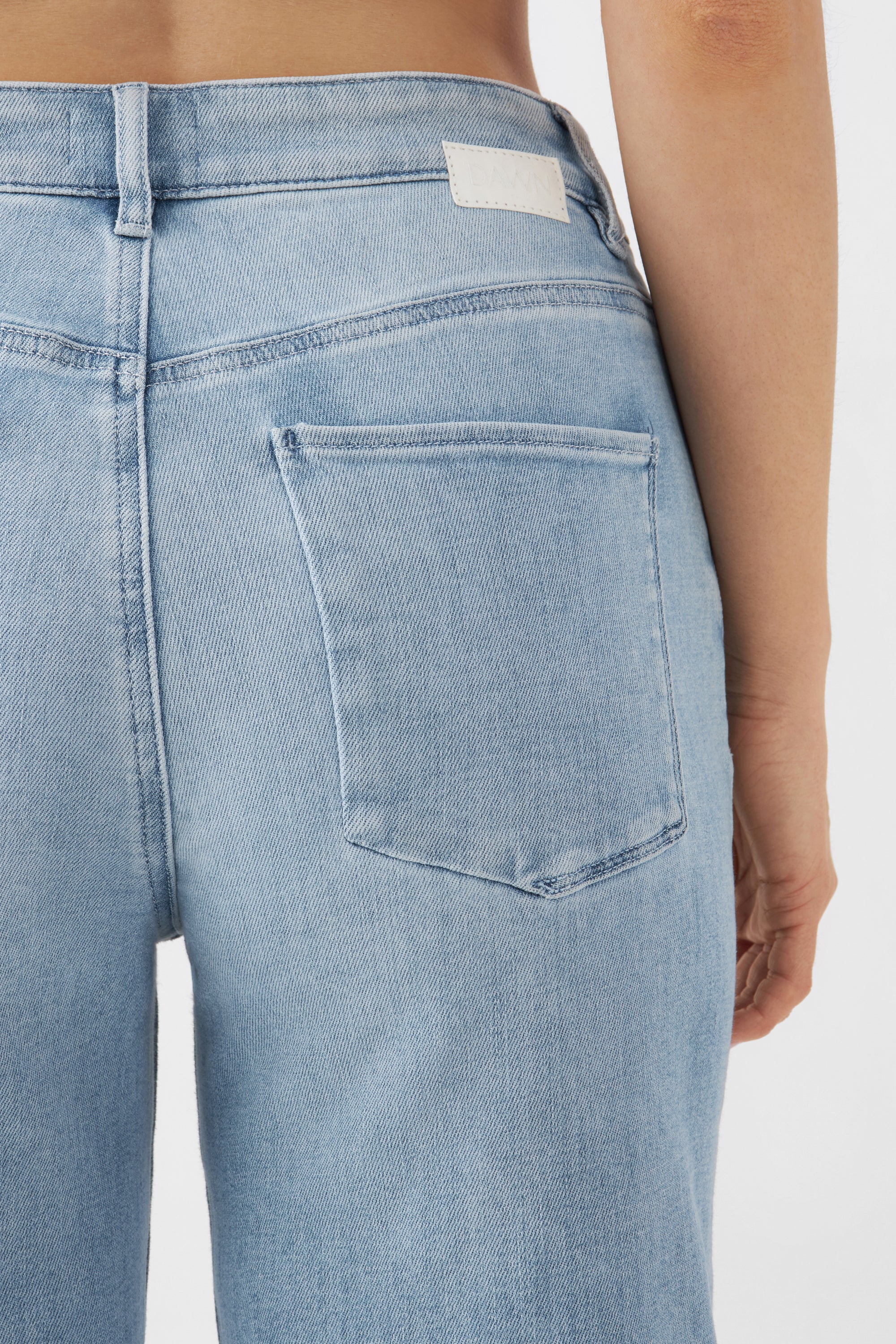 Rückansicht einer hellblauen DEW High-Waist Jeans mit Five-Pocket-Design, sichtbarer Gesäßtasche, Gürtelloops und Bundlabel.