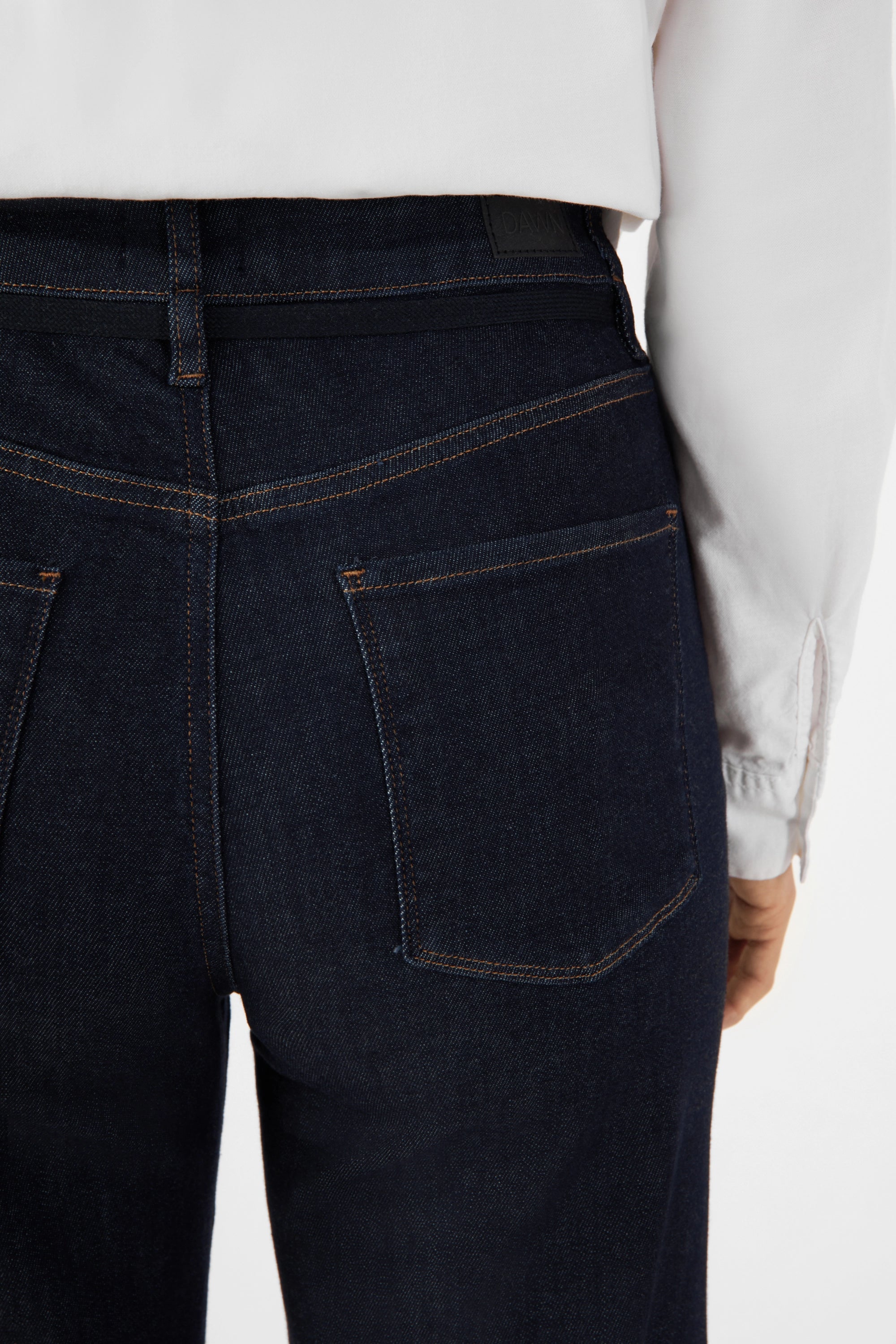 Rückenansicht der DEW Cropped French Pocket Jeans in Raw Blue – dunkelblauer Denim, Kontrastnähte, hohe Taille, ausgestelltes Bein.