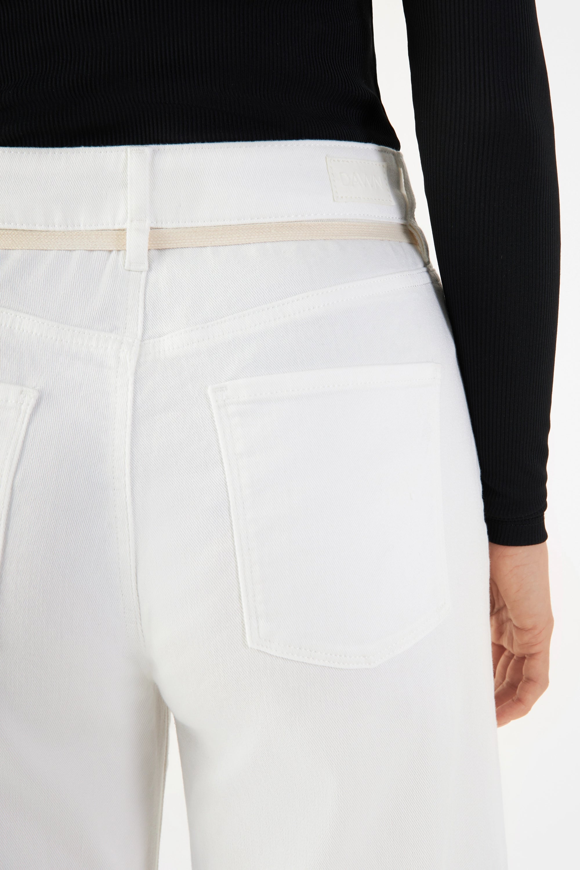 Weiße High-Waist Cropped Flare-Jeans – Rückenansicht mit zwei Gesäßtaschen, beige Gürtelband und DAWN-Label am Bund.