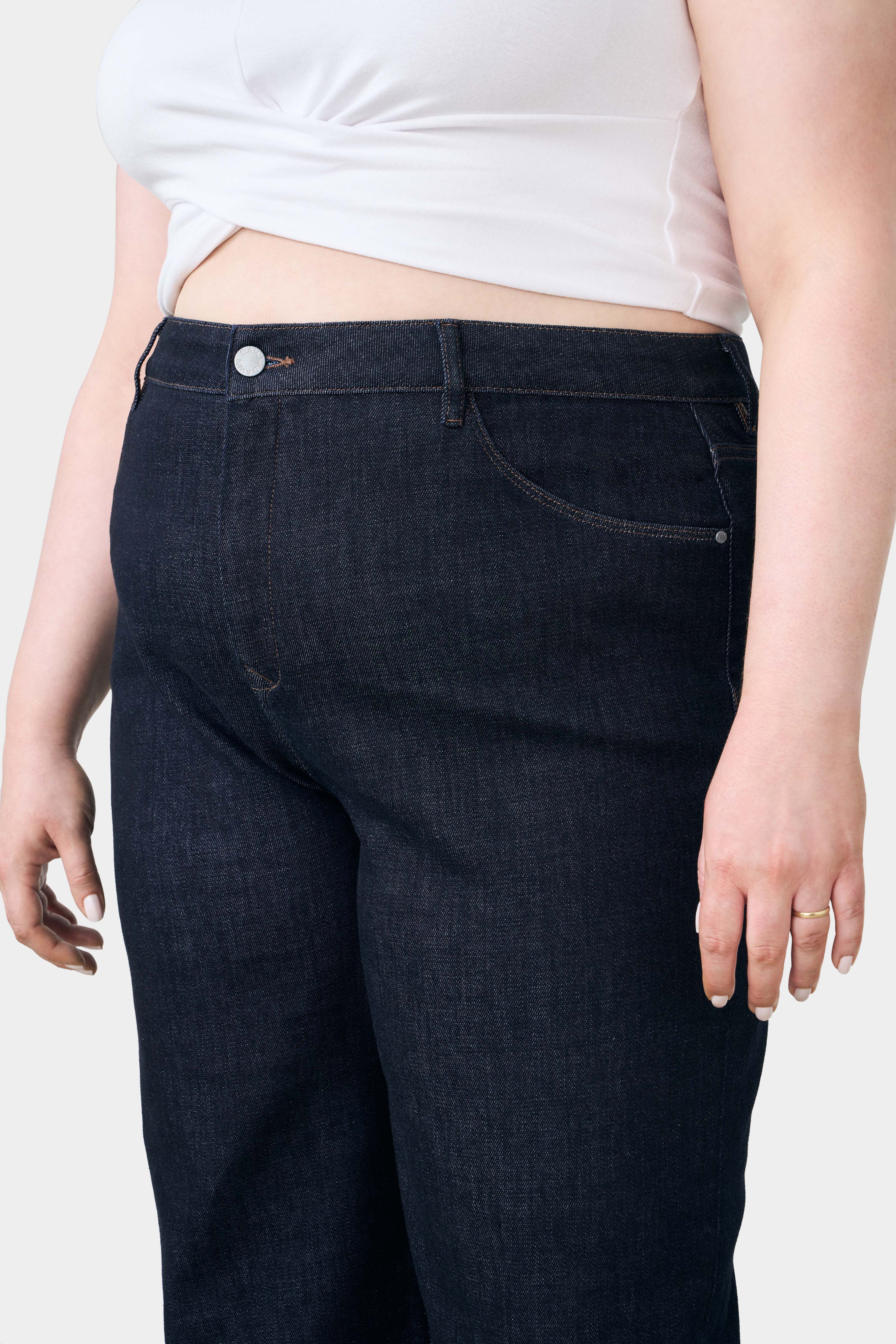 Dunkelblaue DEW Classic Jeans in Raw Blue mit hoher Taille und ausgestelltem Bein; Five-Pocket-Design, Knopfverschluss, Kontrastnähte.