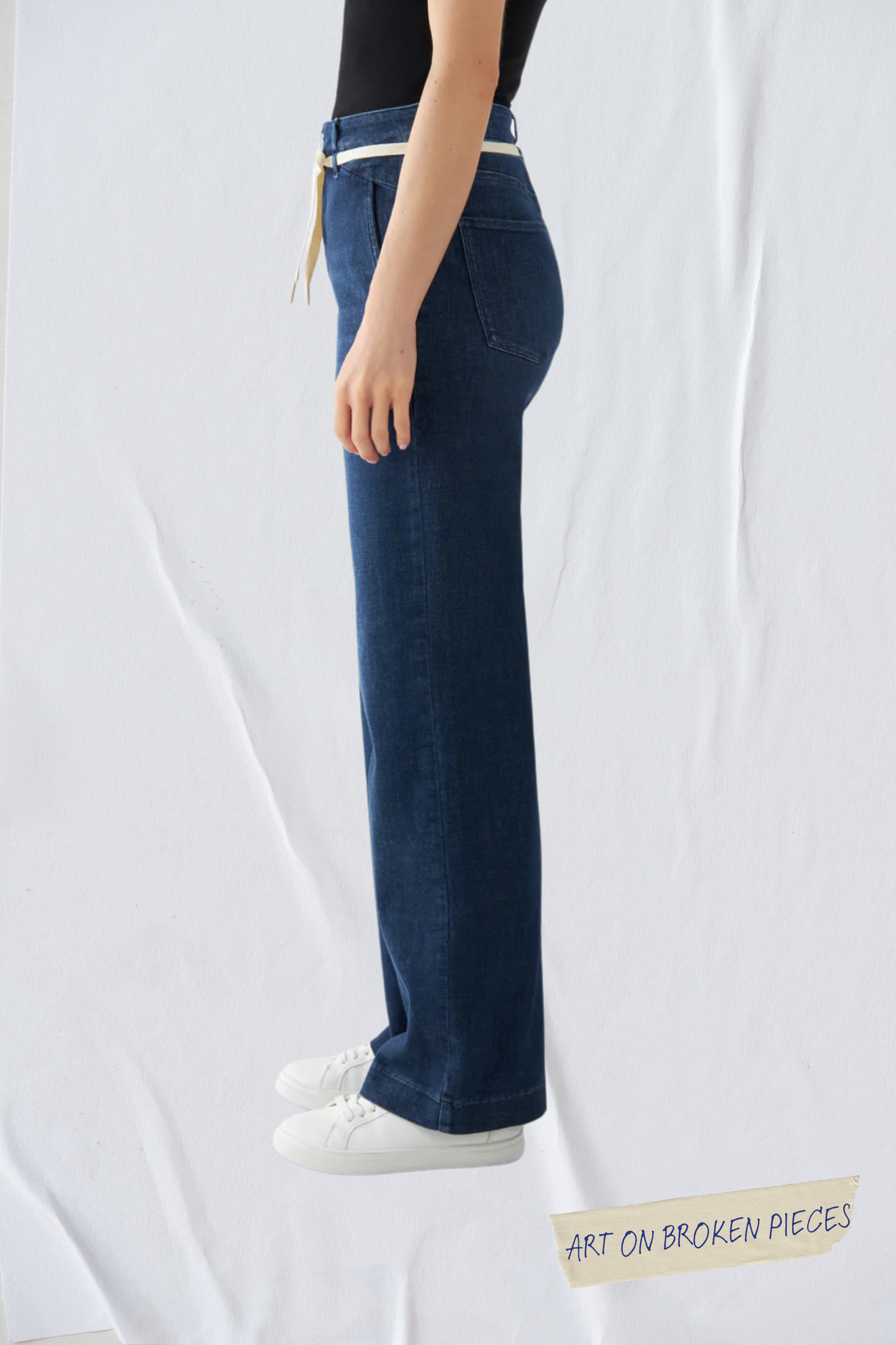 Seitliche Ansicht einer dunkelblauen DEW Flared Soft Denim-Jeans mit hohem Bund, französischen Taschen und weitem Bein.