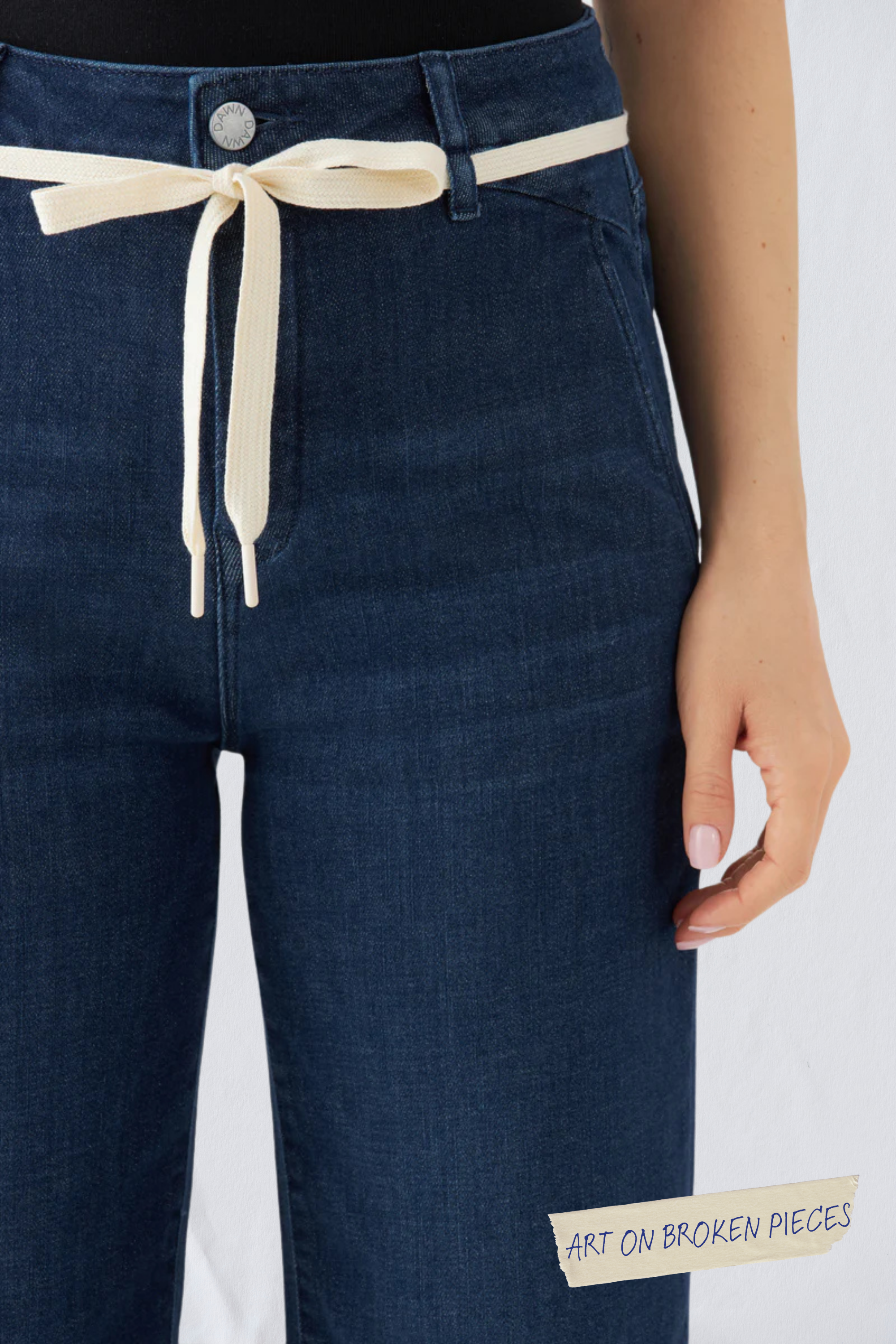 Dunkelblaue DEW French Pocket Flared Jeans, hoher Bund, cremefarbener Kordelzug; sichtbares Label Art on Broken Pieces.