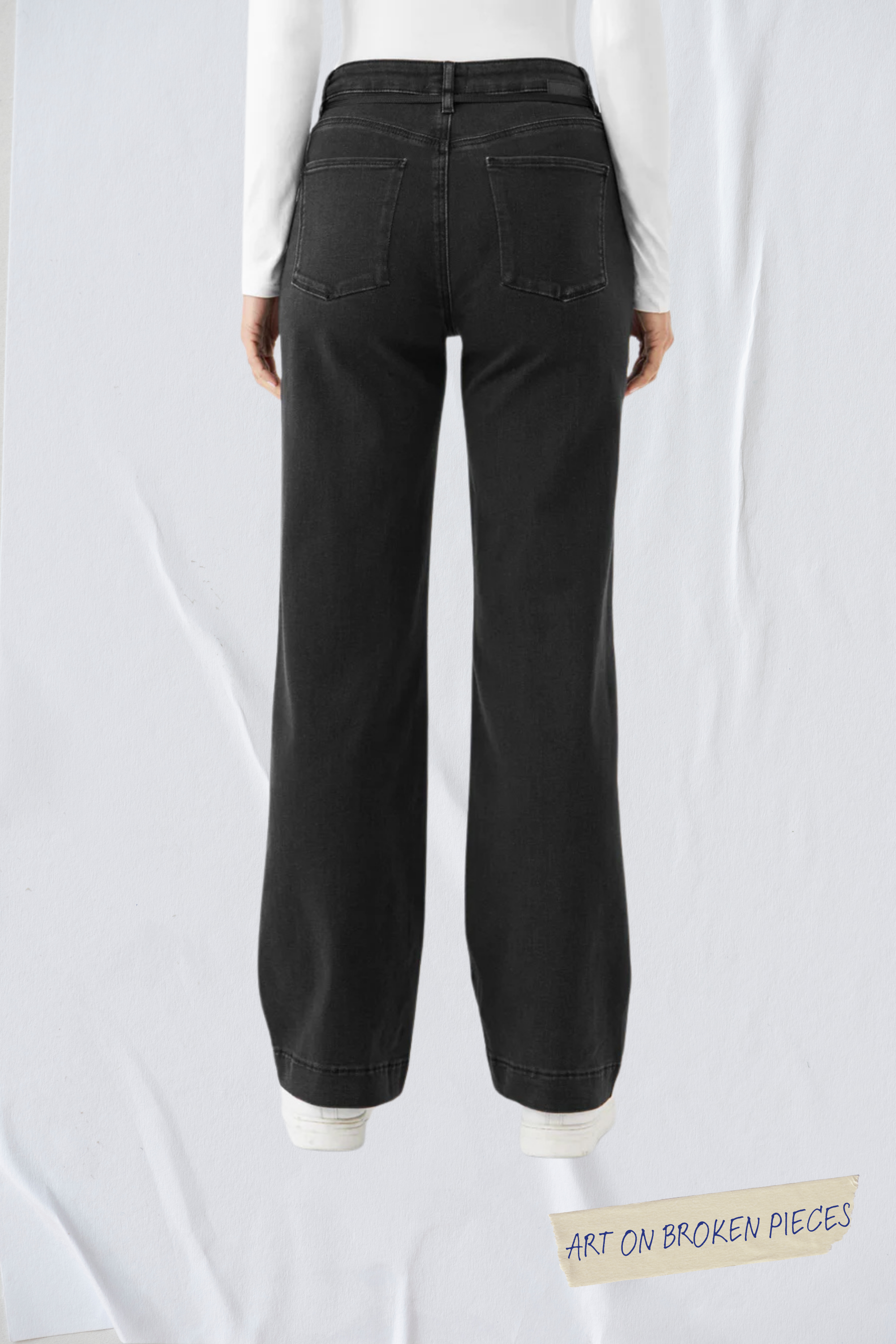 Schwarze DEW Flared Jeans mit hohem Bund, Rückenansicht zeigt zwei Gesäßtaschen; Label Art on Broken Pieces am Bildrand.