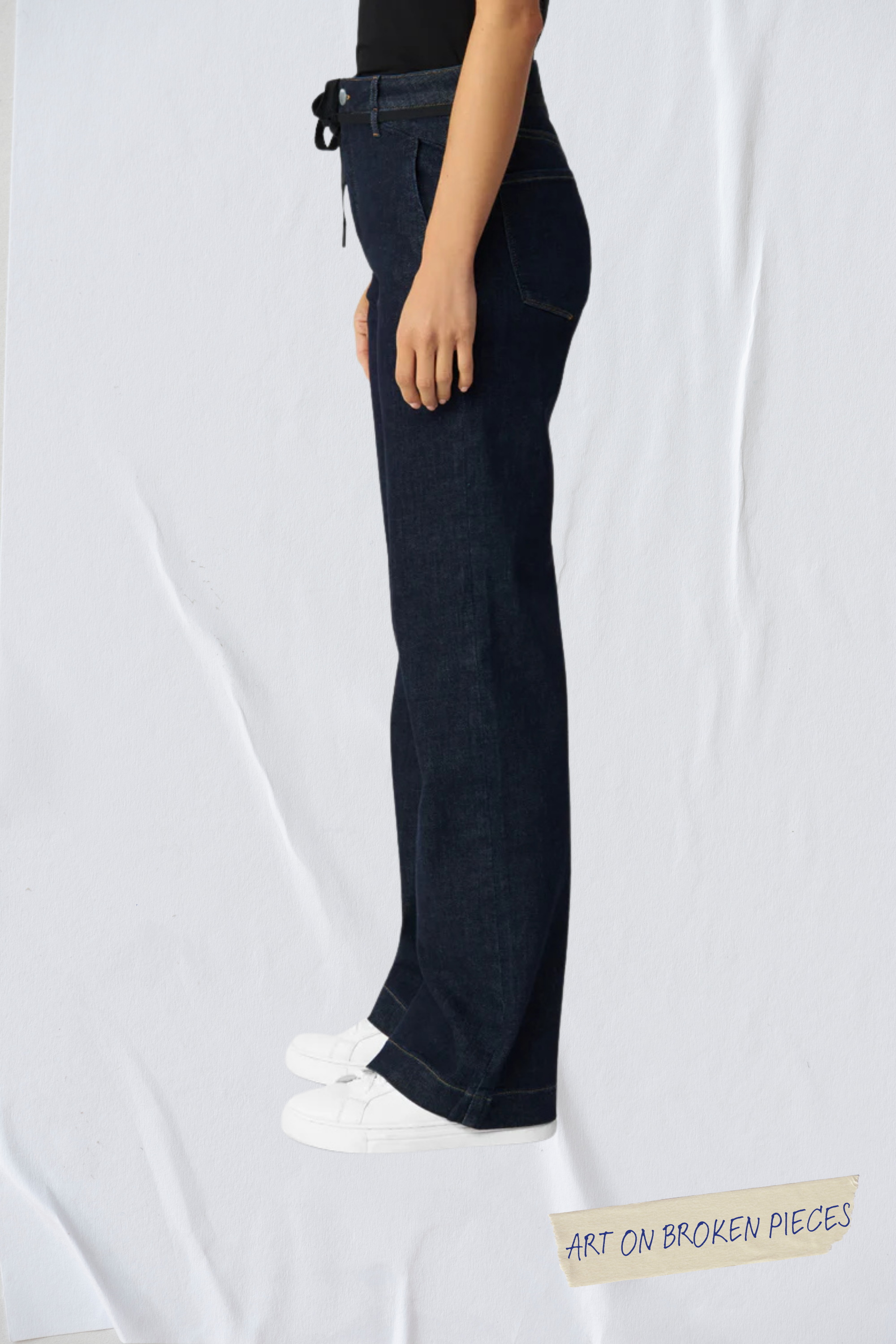 Seitenansicht einer dunkelblauen DEW-Jeans im Flared-Fit mit French Pocket und High-Waist – Bio-Denim, Art on Broken Pieces (Limitierte Edition).