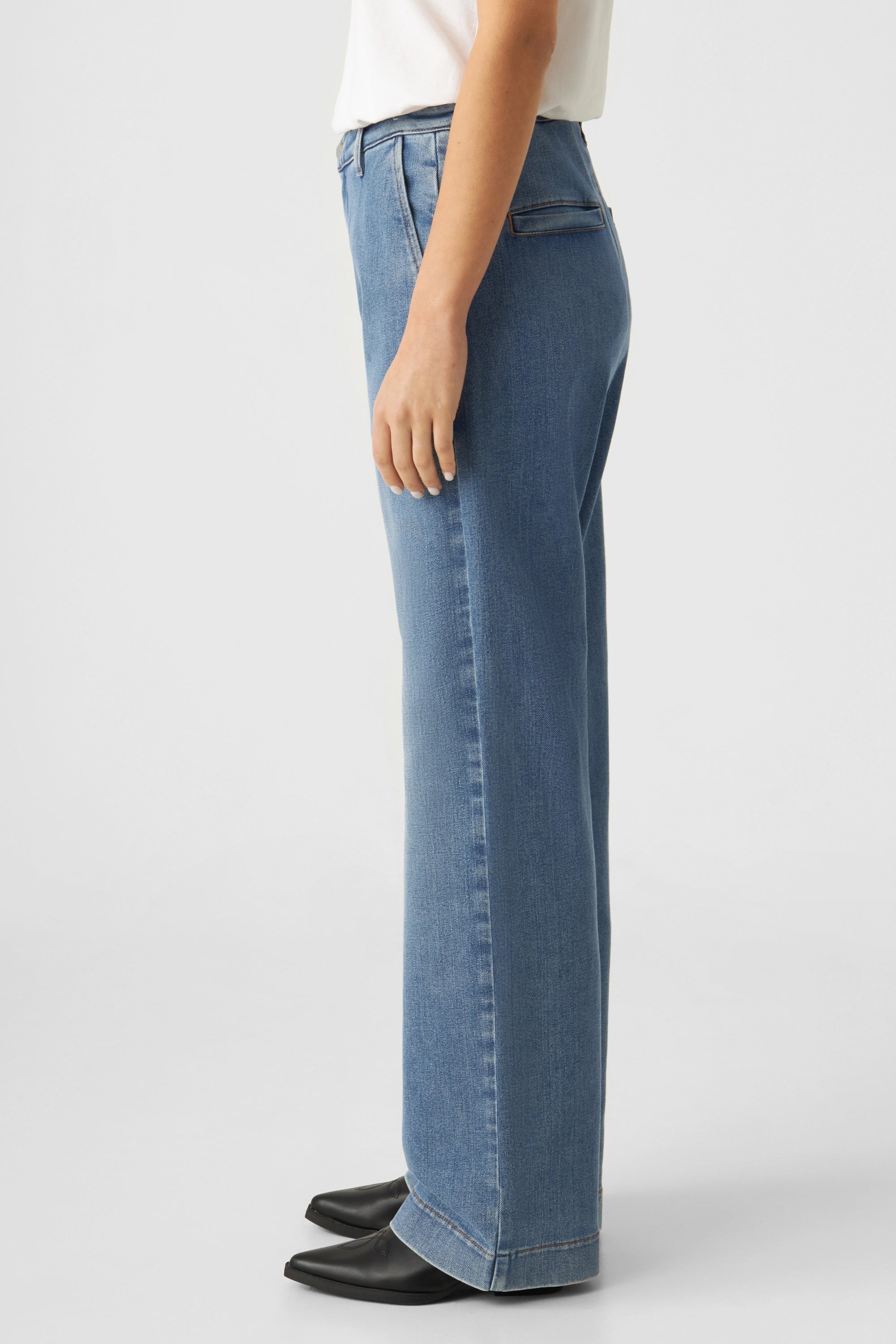 GLOW Flared Soft Denim-Chino, Medium Blue – seitliche Ansicht, mittelhohe Taille, eng an der Hüfte, weit ausgestelltes Bein.