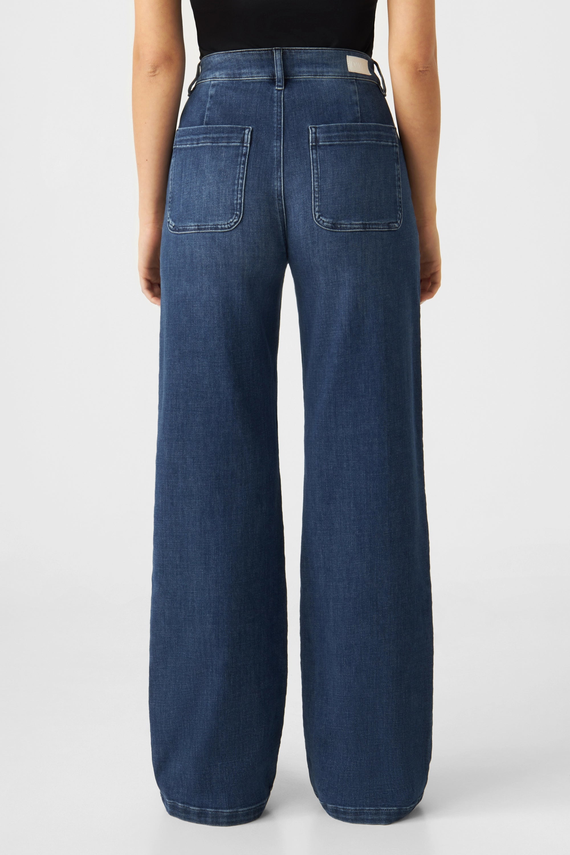 Rückansicht der DEW Flared Soft Denim Worker Jeans in Medium Blue: hohe Taille, weites Bein, große aufgesetzte Gesäßtaschen, Bundlabel sichtbar.