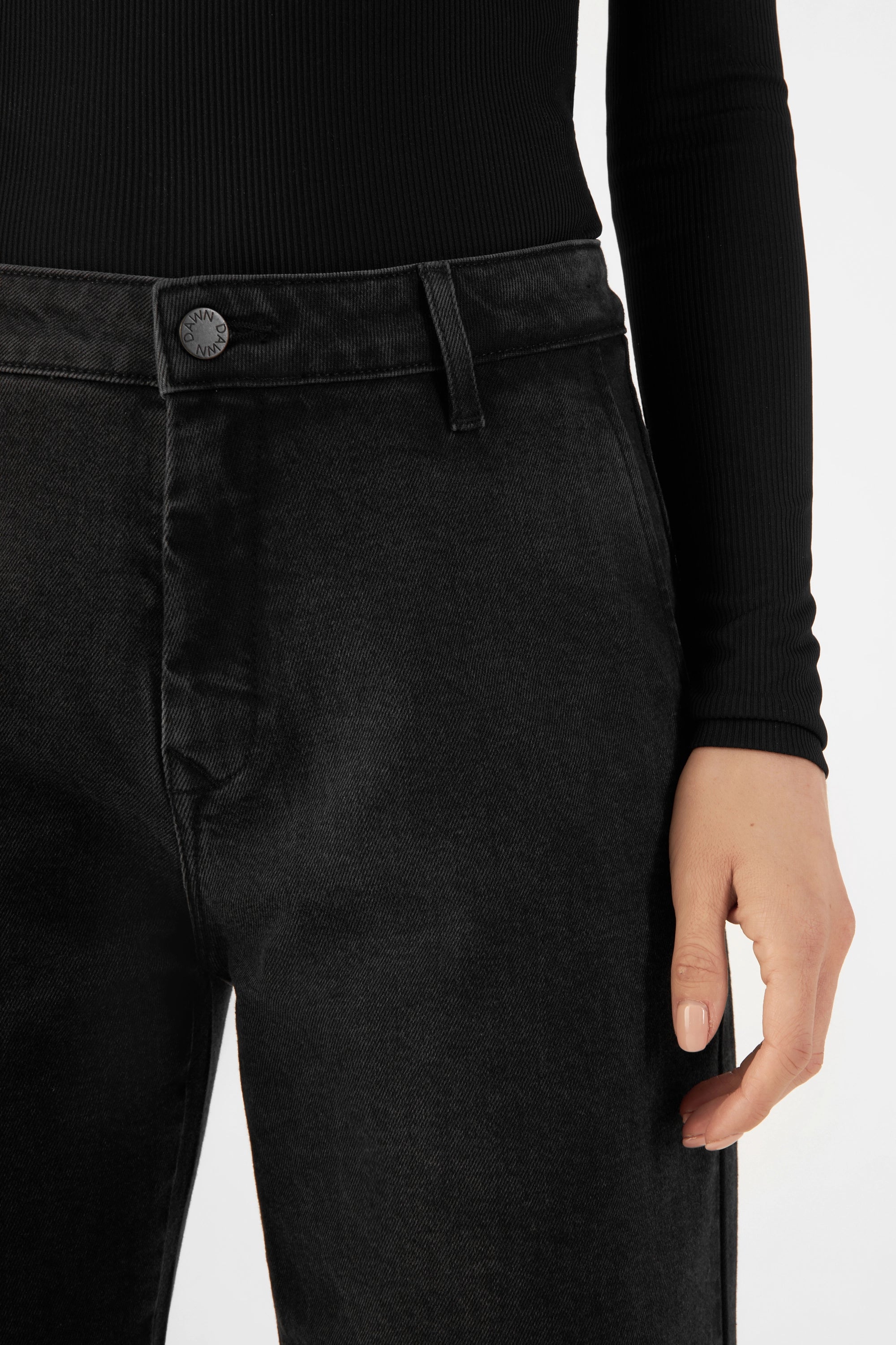 Vintage Black GLOW Denim-Chino: mittelhohe Taille, Knopf und Gürtel, eng an der Taille, ausgestelltes Bein – Nahaufnahme der Vorderseite.