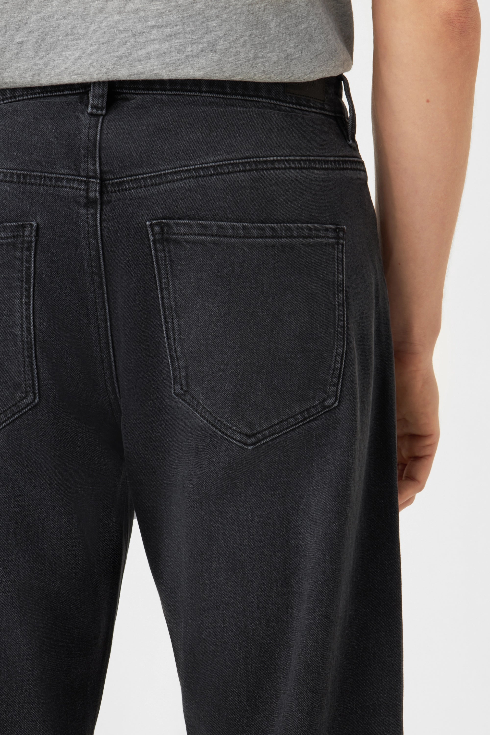 RISE Relaxed Tapered Vintage Black Jeans, Rückansicht mit zwei Gesäßtaschen, dunkler Bio-Denim.