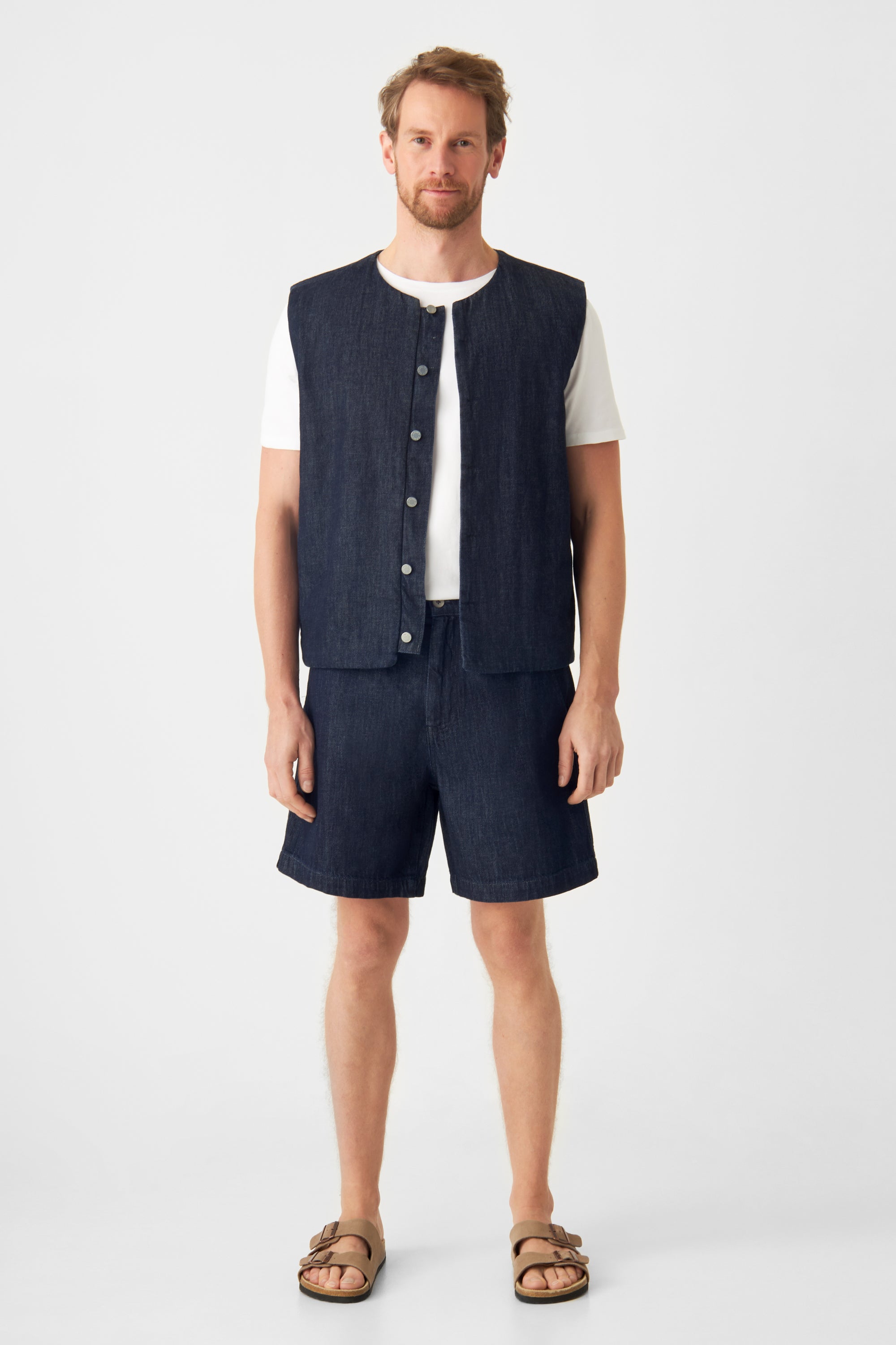 Frontansicht: Mann in Raw Blue SHORTY Shorts aus Lightweight Hemp, mid-rise, weiter Schnitt, kombiniert mit weißem T‑Shirt.