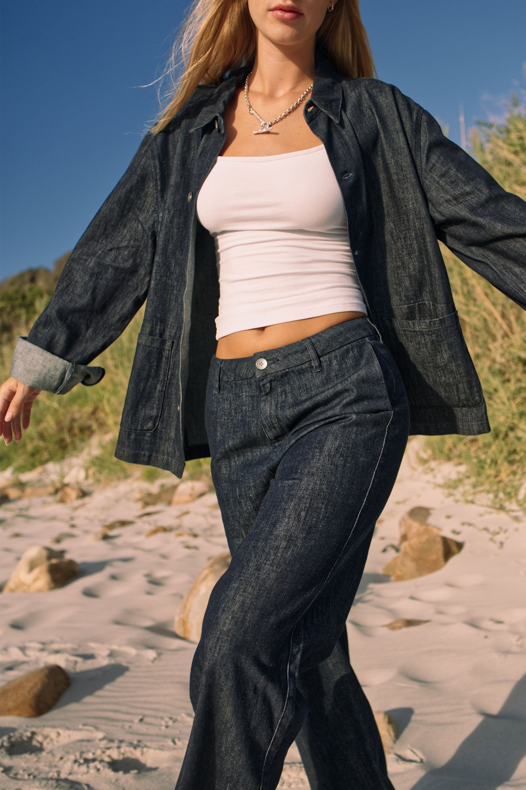 Leichte Hemp-Shacket in Raw Blue mit lockerer Passform, offen getragen über einem weißen Crop-Top; Fronttaschen und aufgerollte Ärmel.