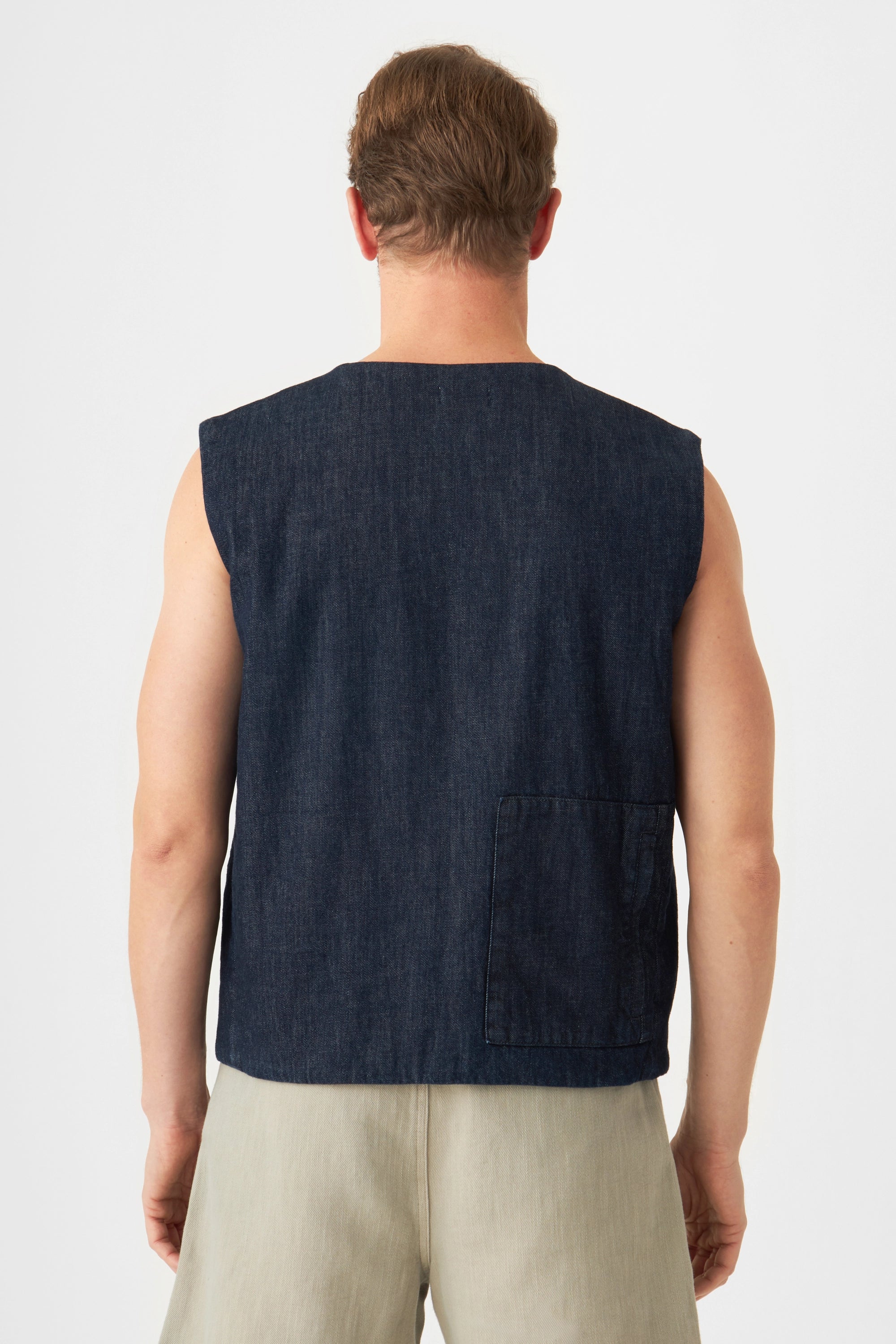 Rückansicht eines dunkelblauen, ärmellosen Hemdjacken-Vests aus Lightweight Hemp; mit einer quadratischen Patchtasche am unteren Rücken.
