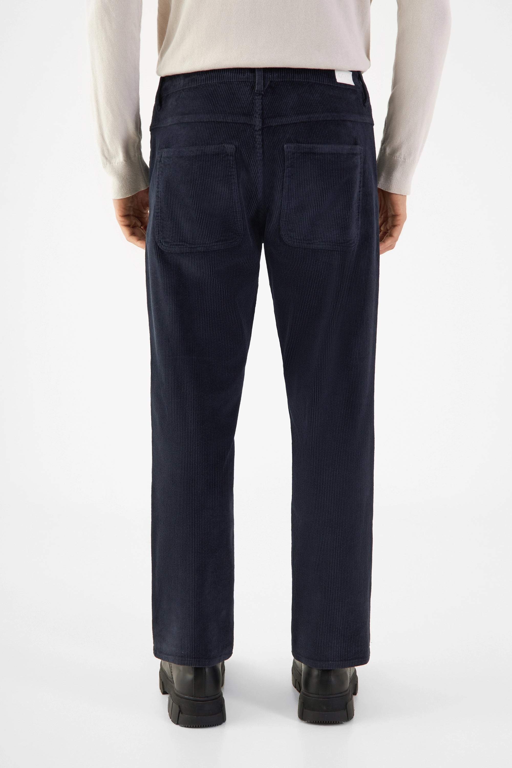 Rückansicht einer dunkelblauen MANE Corduroy-Hose im relaxed straight-Schnitt, mit mittelhohem Bund und zwei hinteren Patchtaschen.