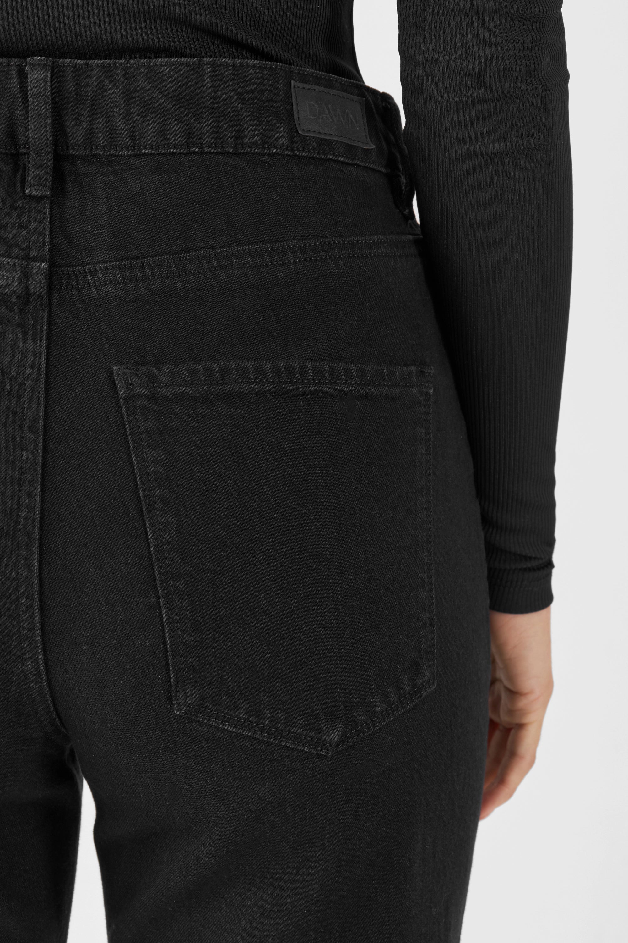 Rückansicht einer schwarzen MORNING Jeans von DAWN – 5-Pocket-Design, mittlere Taille, sichtbare Gesäßtasche und Bund-Label.