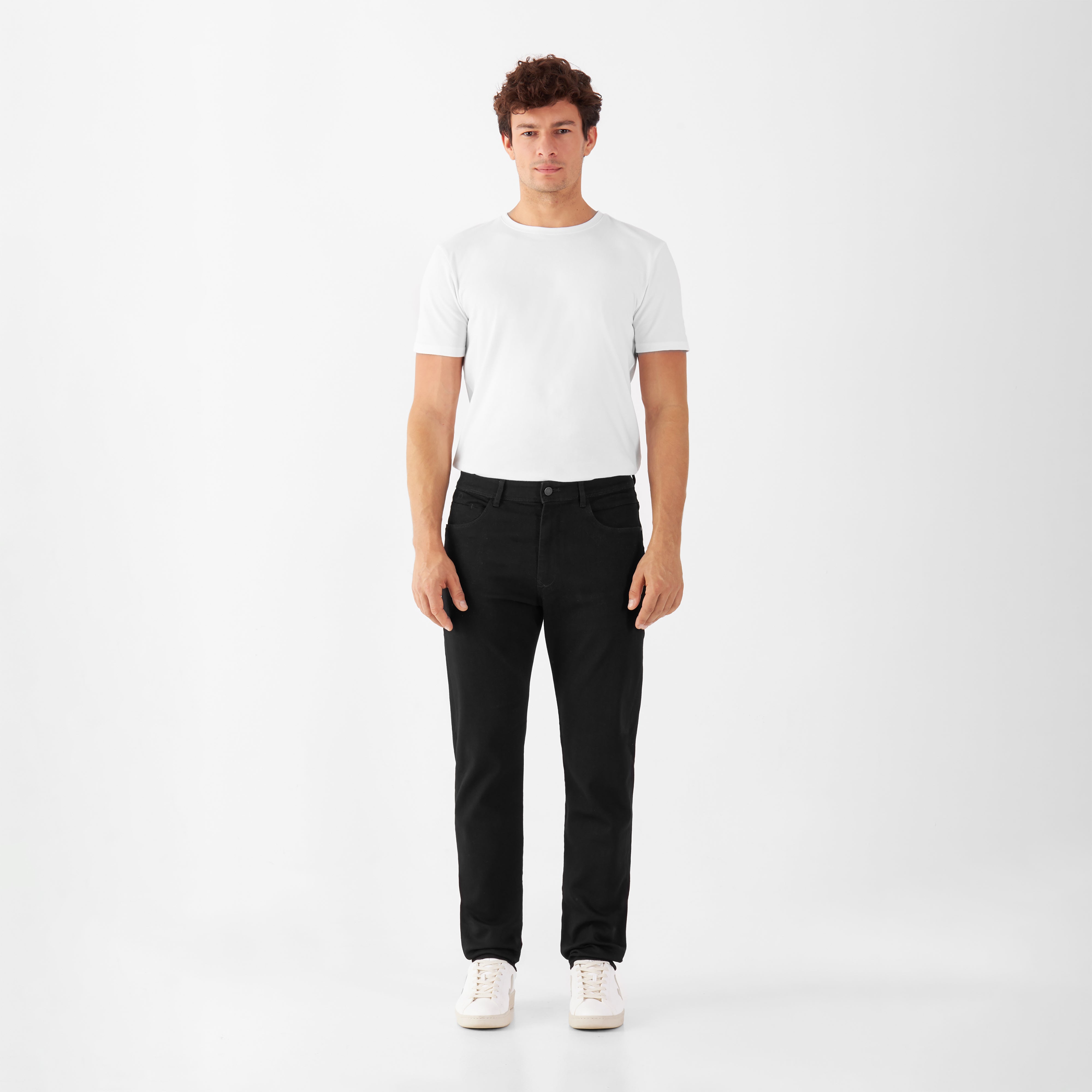 Schwarze MORROW Slim Fit Jeans mit Komfortstretch, mittlere Taille, leicht zulaufendes Bein; Mann trägt weißes T‑Shirt.