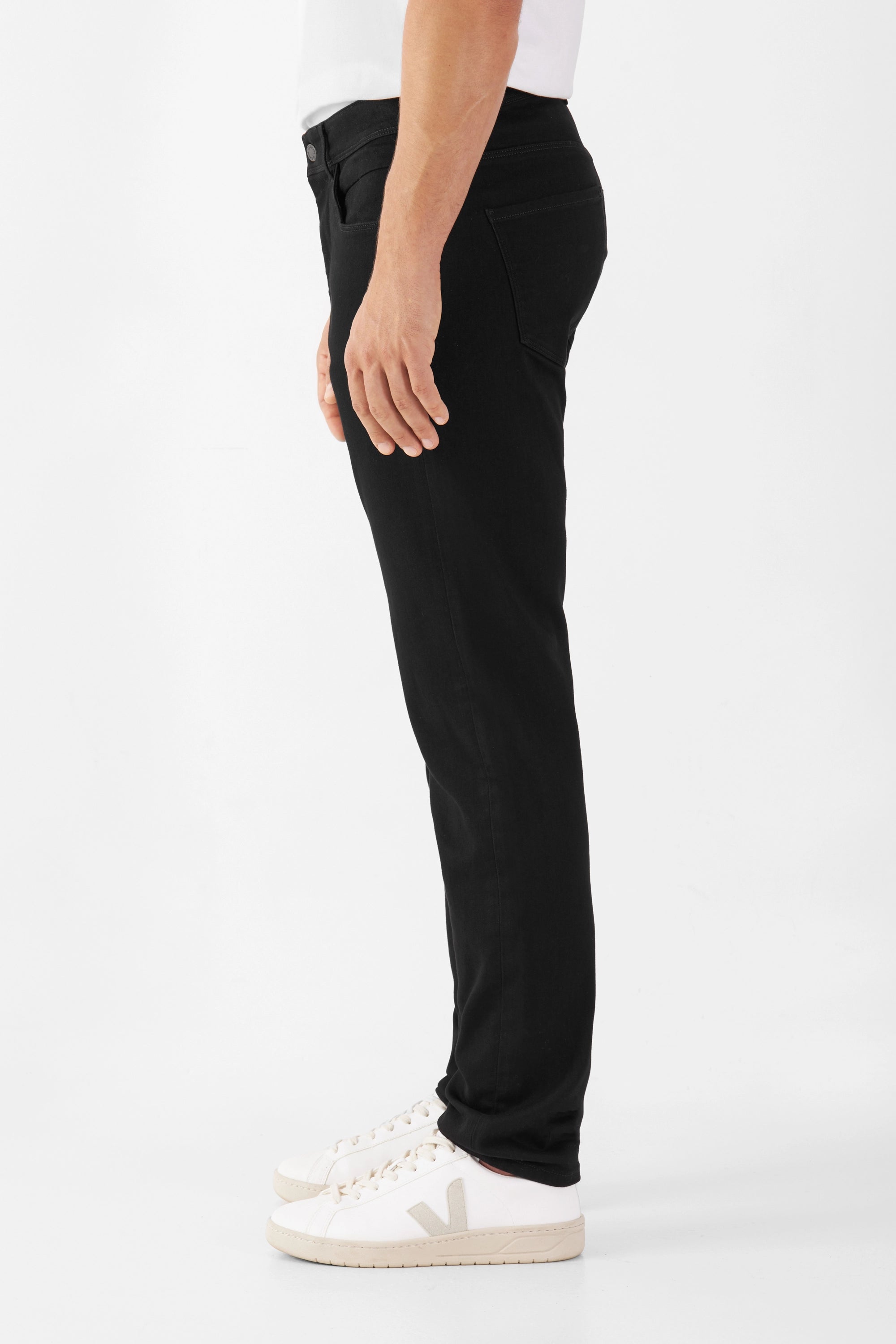 Schwarze MORROW Slim-Fit Jeans aus Organic Comfortstretch, mittlere Taille, leicht zulaufendes Bein – Seitenansicht eines Modells mit weißen Sneakern.