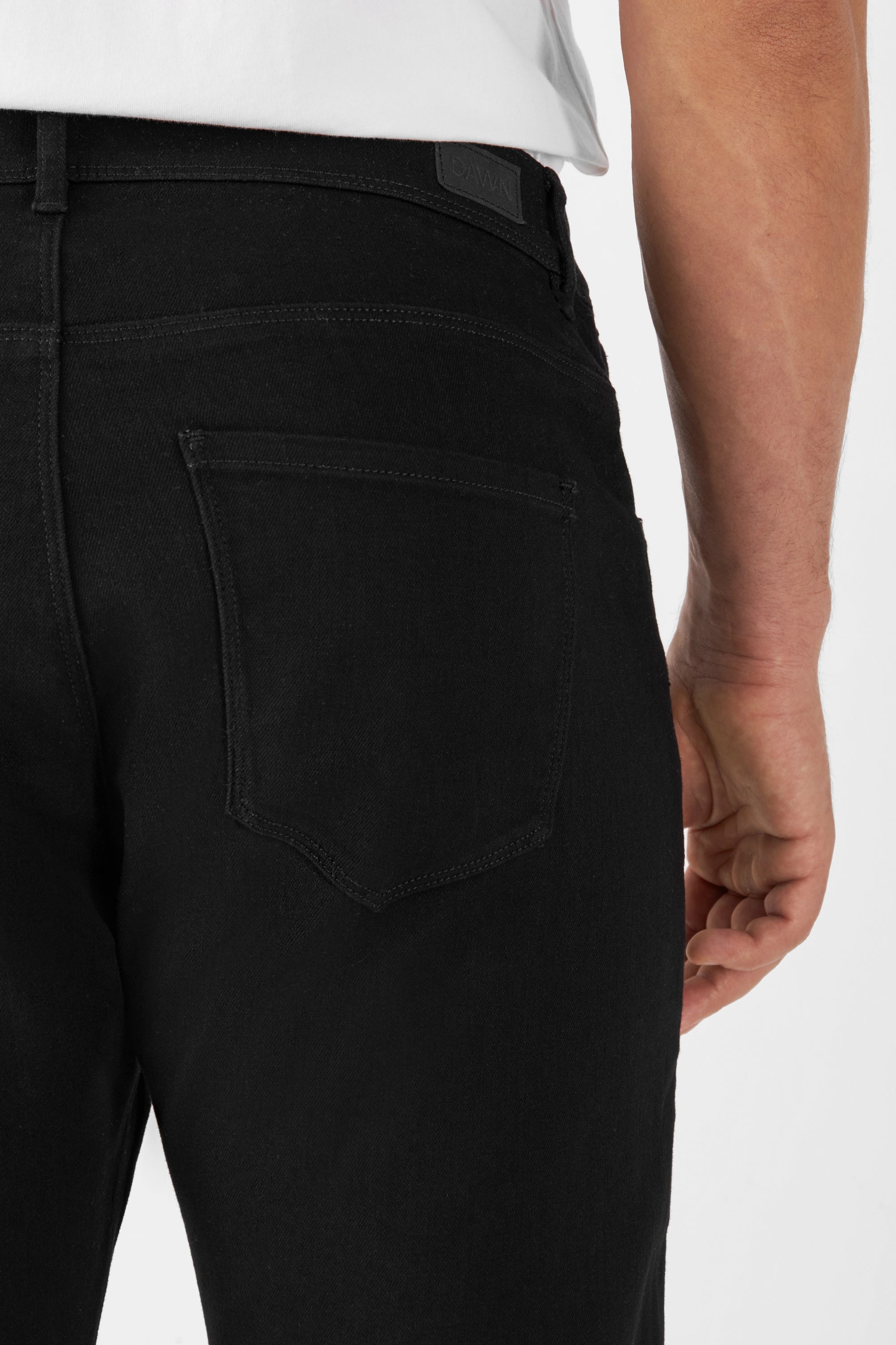 Schwarze MORROW Slim-Fit Jeans von DAWN, Rückseite mit einer Gesäßtasche und Logo-Patch am Gürtelband, gefertigt aus Organic Comfortstretch-Denim.