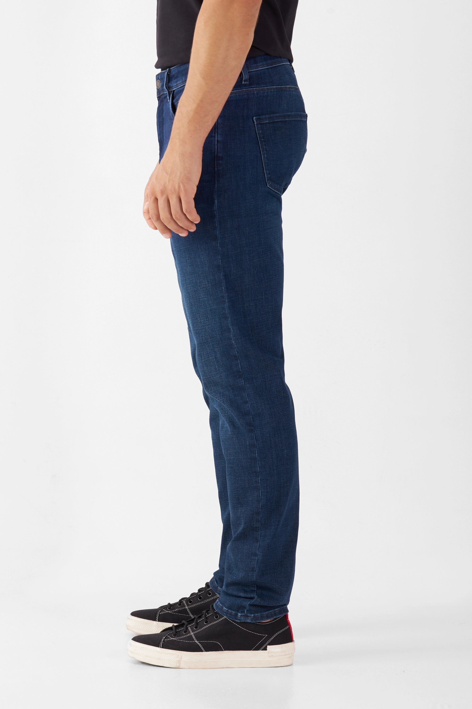Dunkelblaue MORROW Slim-Fit Jeans mit Komfortstretch, mittlere Taille, leicht zulaufendes Bein – Seitenansicht eines Models.