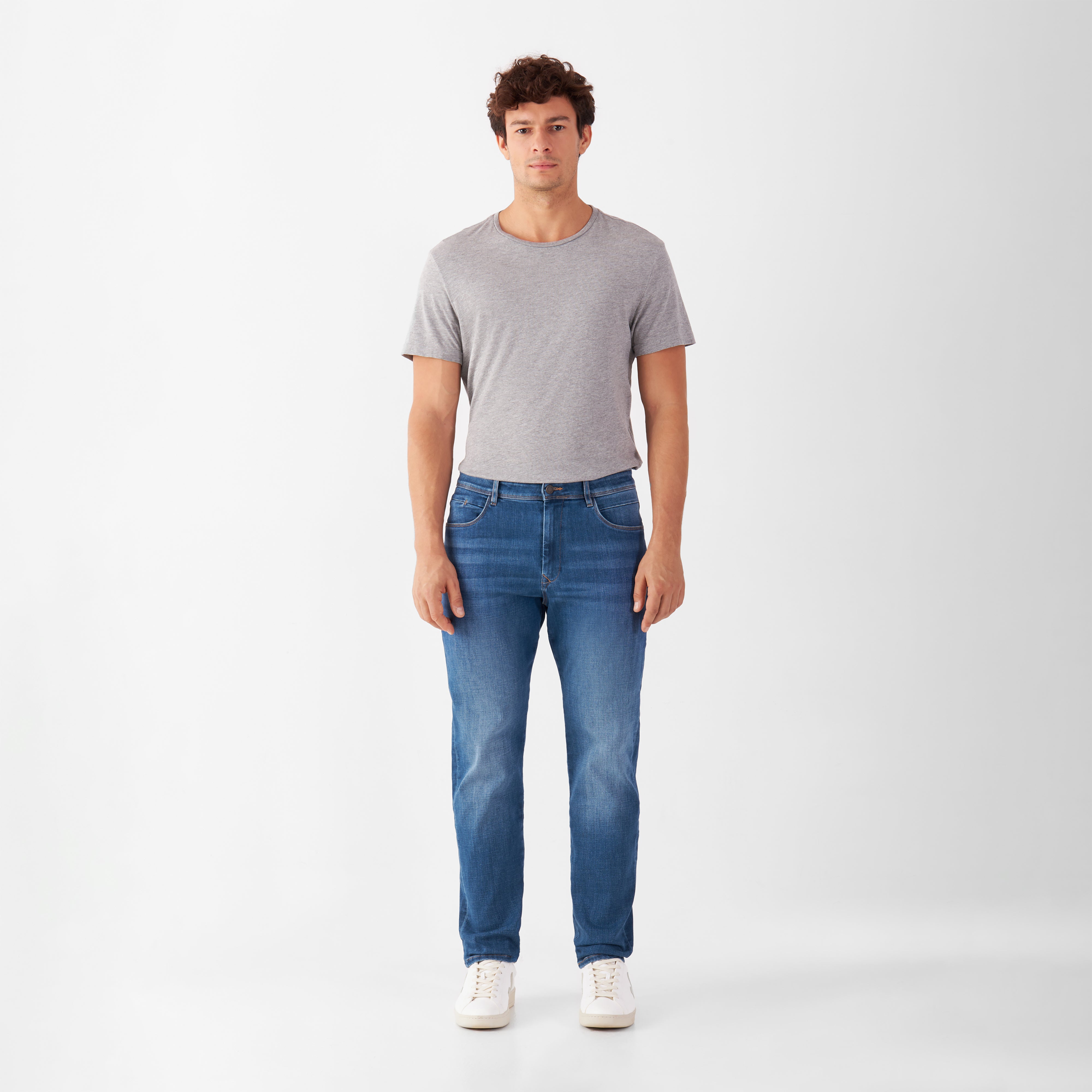 MORROW Soft Stretch Slim Jeans in Medium Blue, Frontansicht eines Mannes mit grauem T‑Shirt; mittlere Taille, leicht zulaufendes Bein.