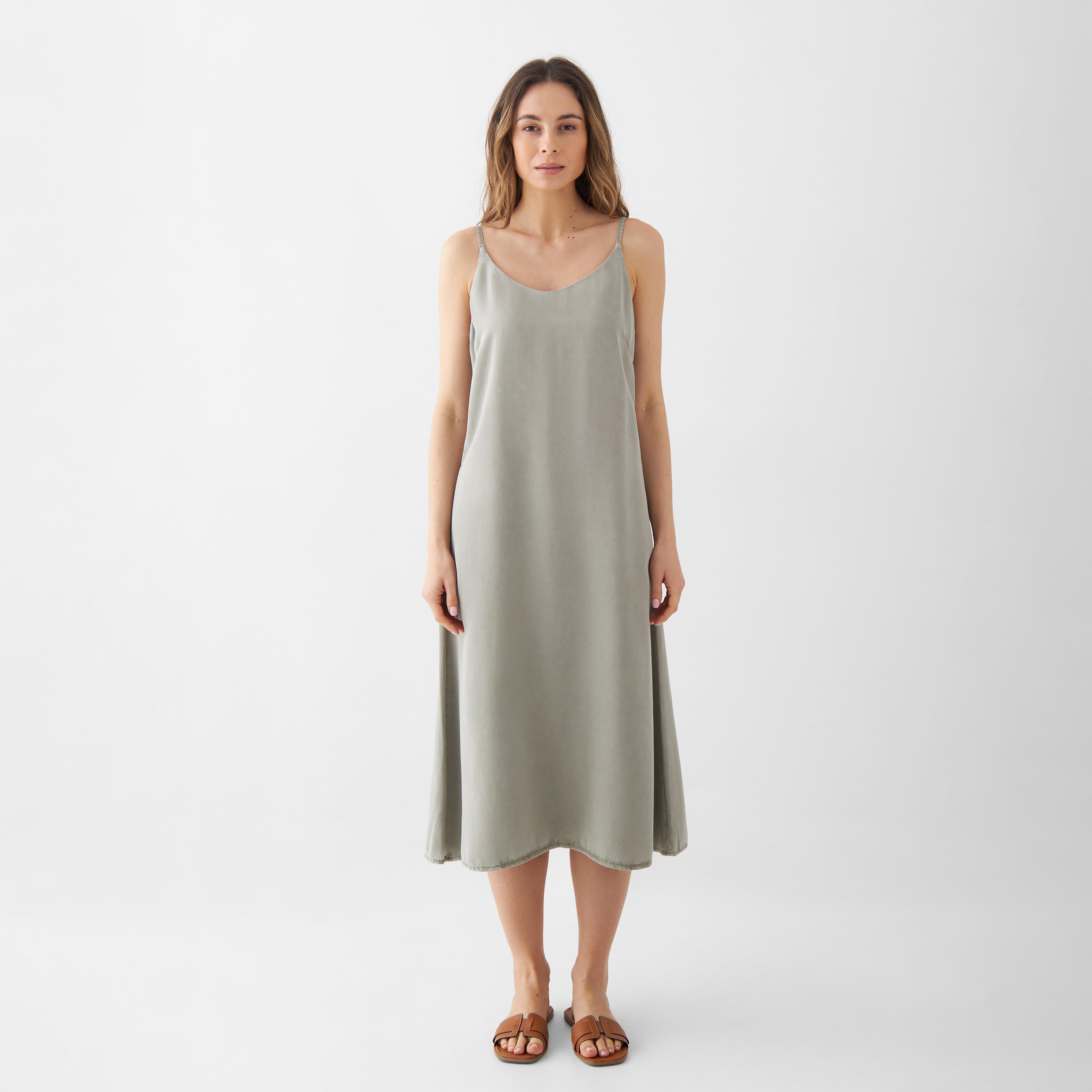 SUNBEAM Midikleid Olive aus Lyocell, lockere A-Linie, V-Ausschnitt, verstellbare Träger, seitliche Taschen, getragen von einer Frau.