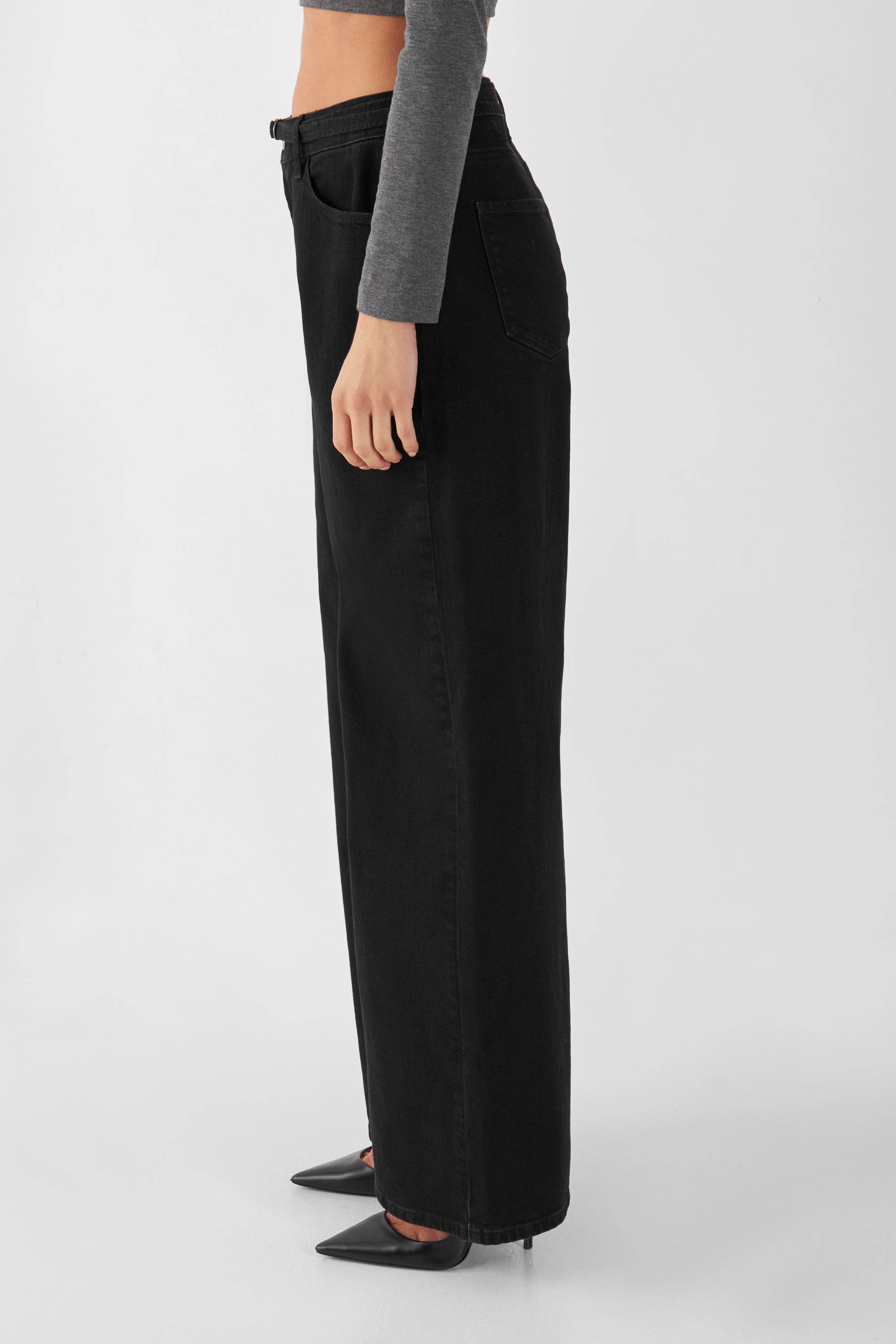 DAWN SUNNY Wide Leg Jeans – Schwarz, mittelhohe Taille, weites gerades Bein; Denim-Gürtel sichtbar, Seitenansicht mit Pumps.