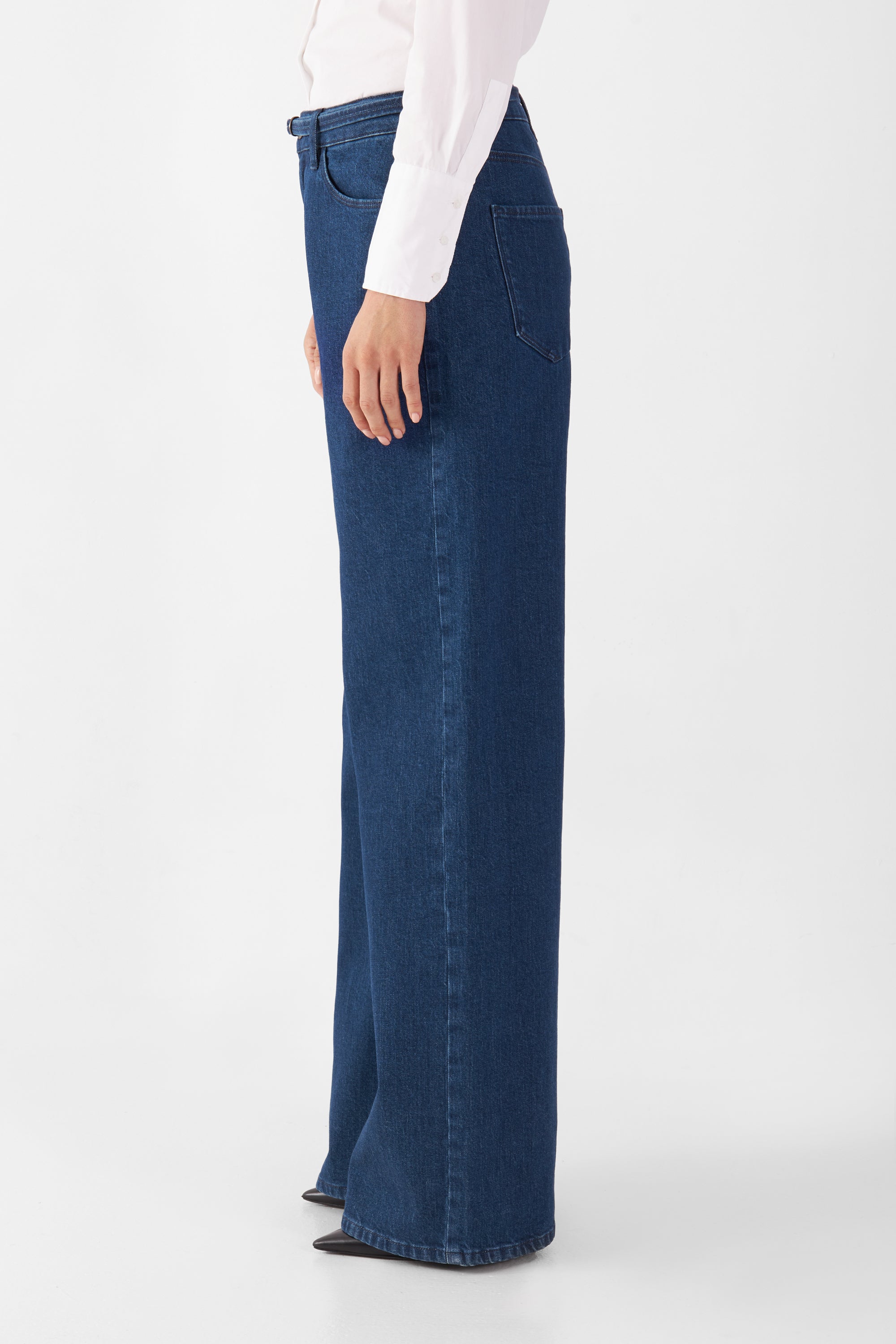 Dunkelblaue Sunny Wide Leg Jeans mit mittelhoher Taille und weiterem geradem Bein, Seitenansicht einer Person in weißem Hemd.