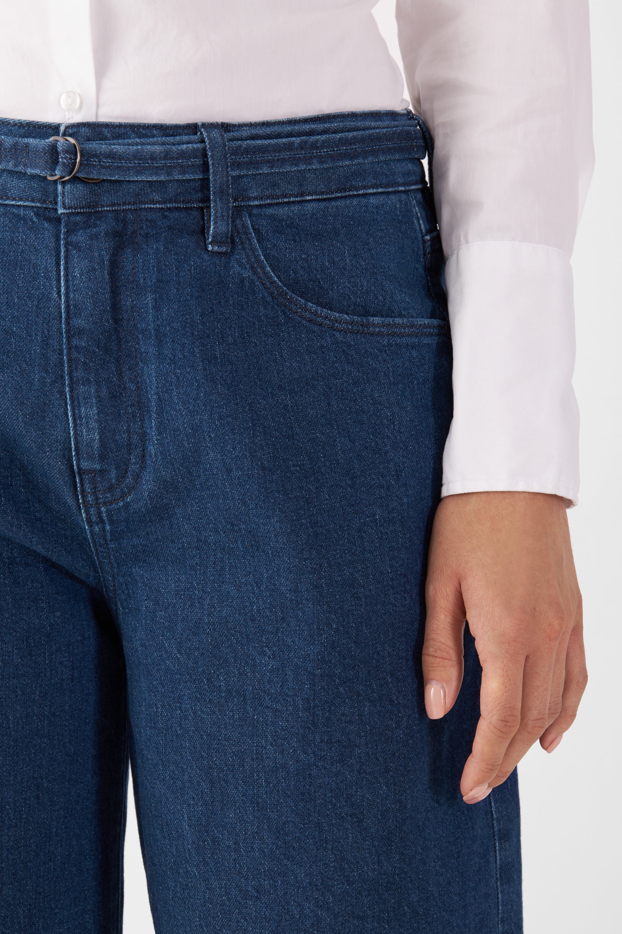 Dunkelblaue Denim-Jeans von DAWN, Vorderansicht mit breitem Bund, Gürtel-Schlaufe und Fronttasche; weiße Bluse eingesteckt.
