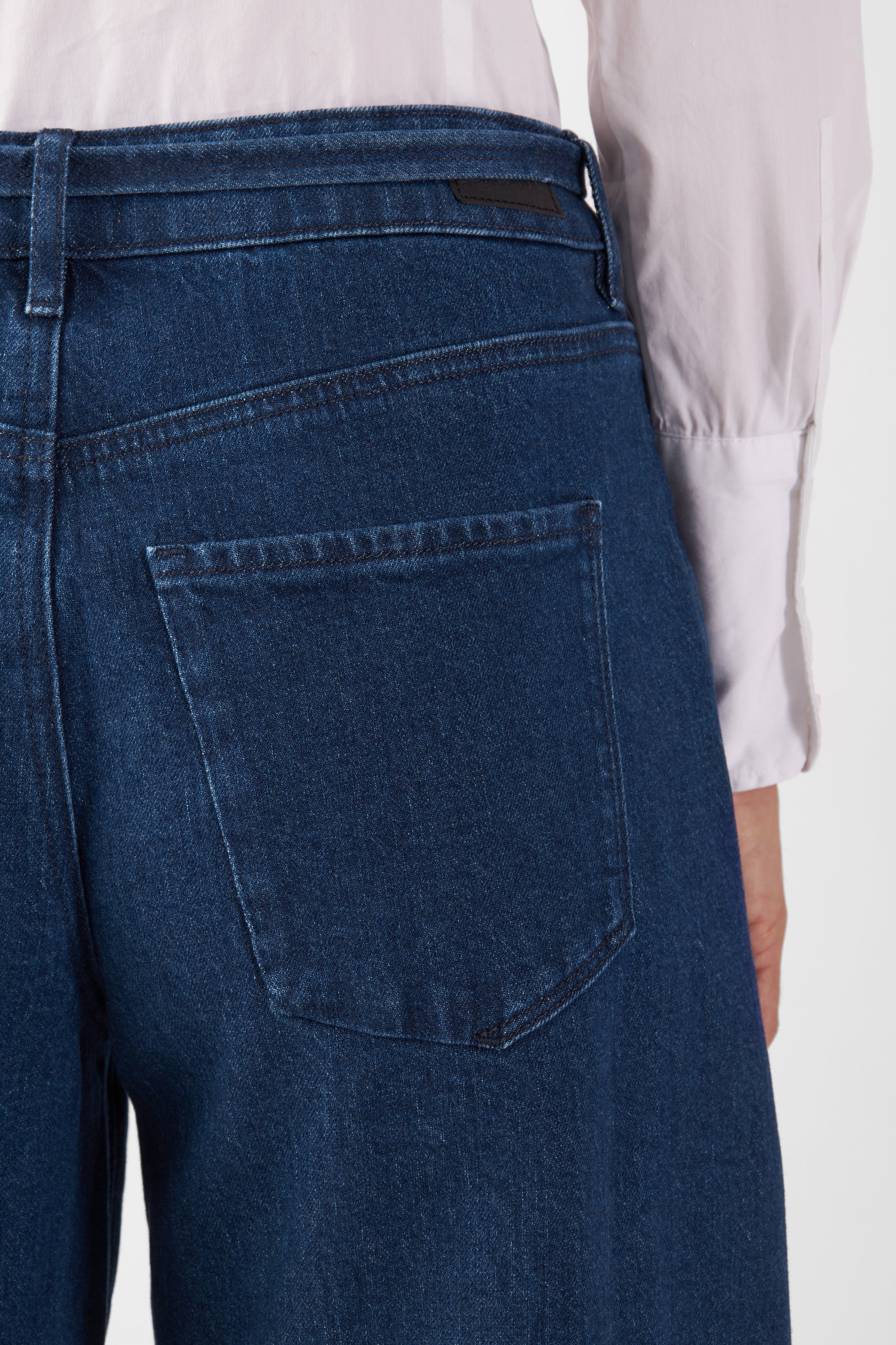 Rückansicht einer dunkelblauen Jeans mit mittelhoher Taille und weiterem geradem Bein, Gesäßtasche und Gürtelschlaufen sichtbar.