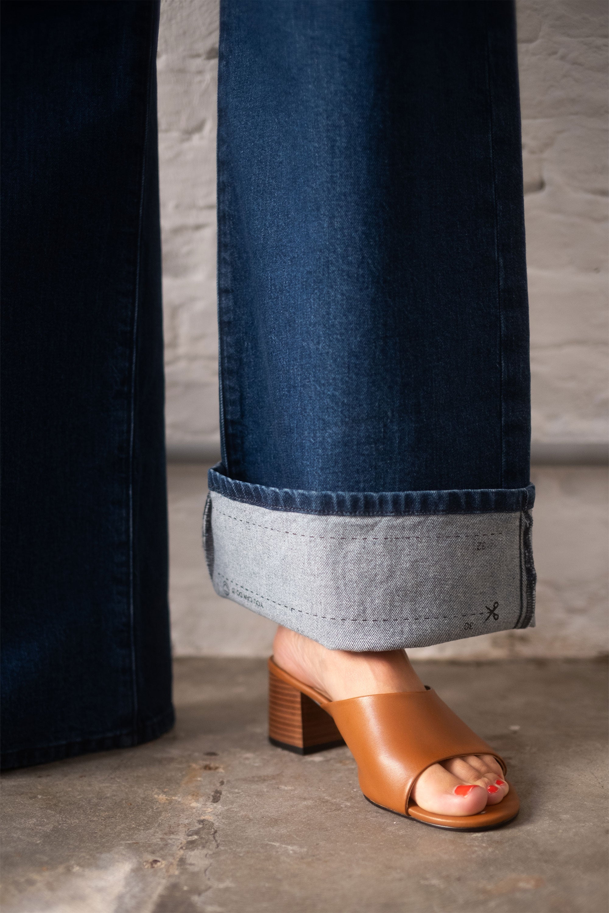 Dunkelblaue SUNNY Wide Leg Jeans mit mittelhoher Taille und weitem geradem Bein; Saum umgekrempelt, helle Innenkante sichtbar.