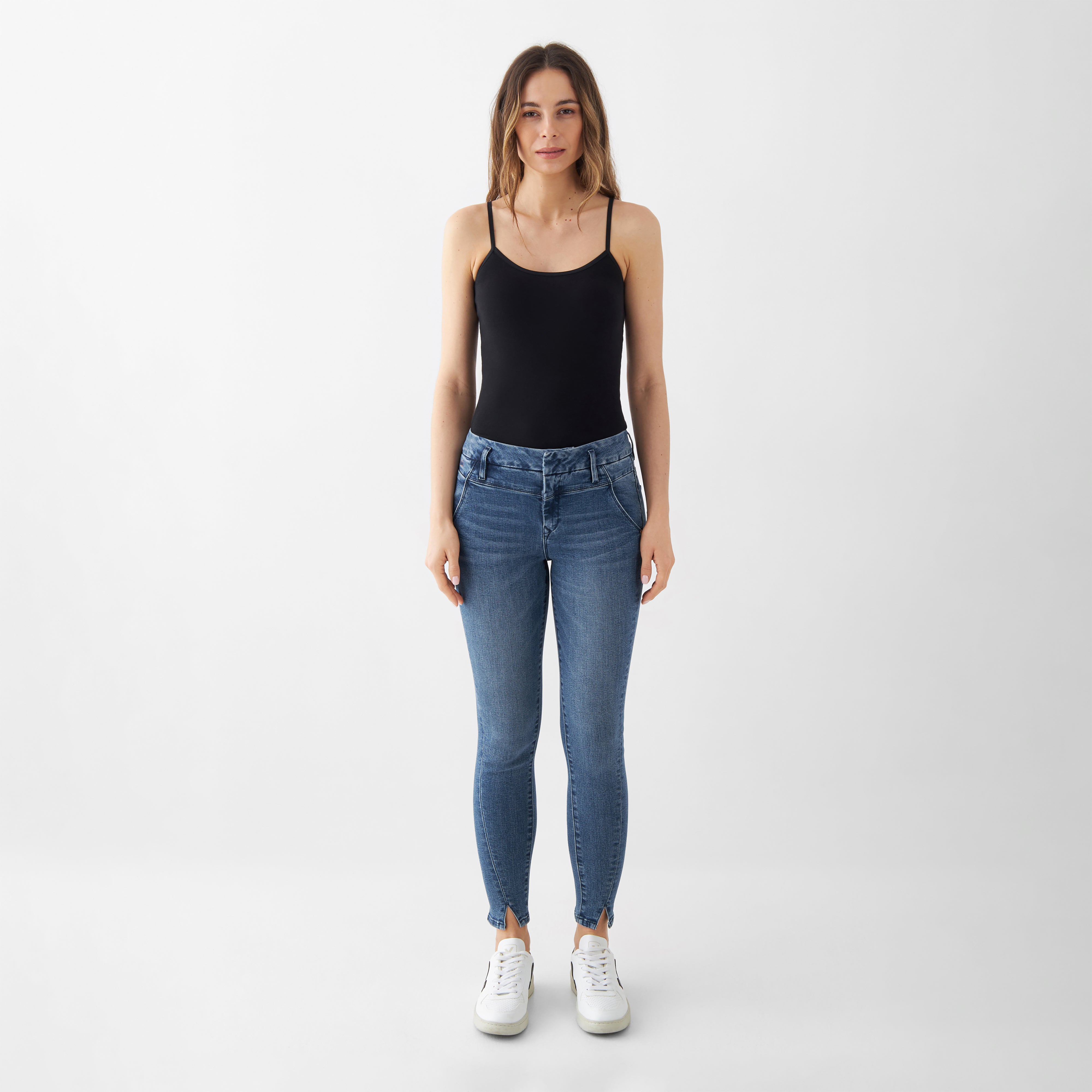 SUN UP Skinny Jeans in Medium Blue mit schräge Außennähte und Saumschlitz; Powerstretch-Denim formt die Figur, getragen von Model im schwarzen Top.