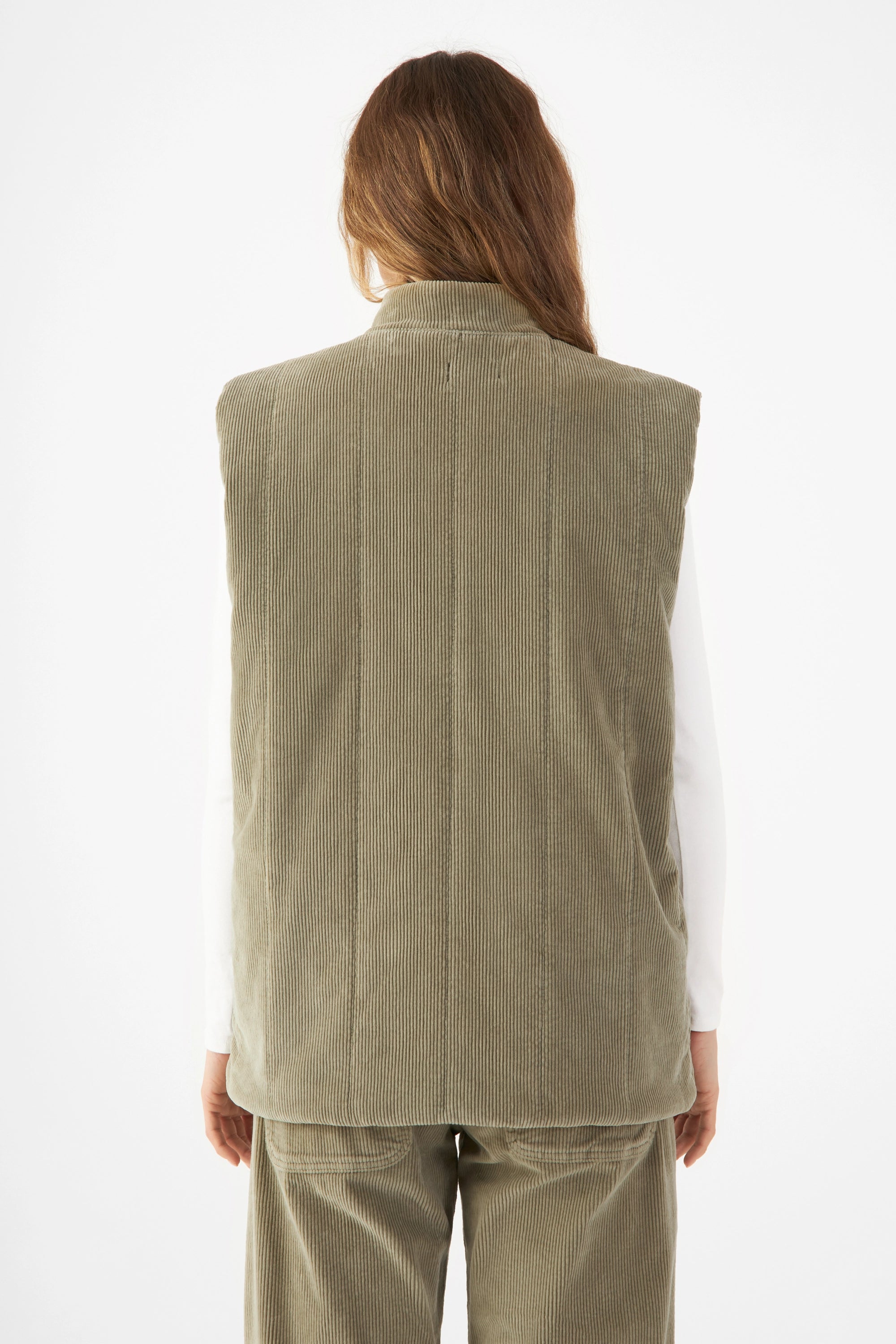 Rückenansicht einer wattierten Corduroy-Weste in Sage Green, vertikale Steppung, lockerer, kastiger Schnitt.