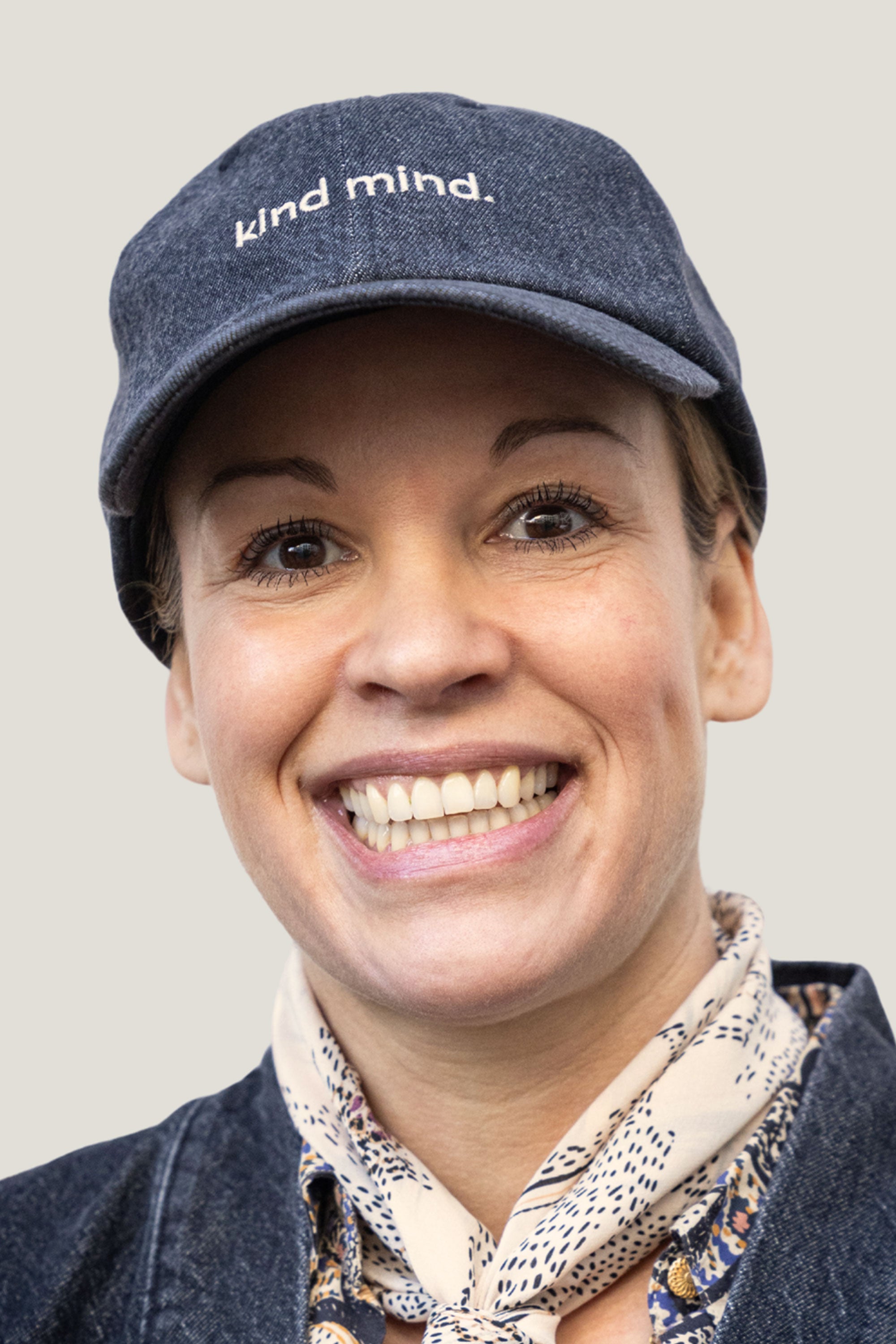 Dunkelgraue Denim-Kappe mit 'kind mind'-Aufdruck, getragen von einer lächelnden Person – nachhaltiges Limited Edition Cap aus Bio-Denim.